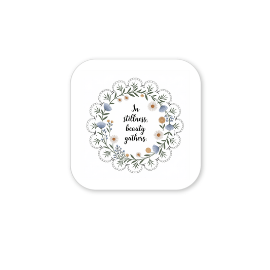 The Mirabilia Boutique In Stillness Beauty Gathers Floral Quote Magnet features a square design with a wreath of green leaves and flowers around the handwritten quote—an inspiring mindfulness accent for any space.