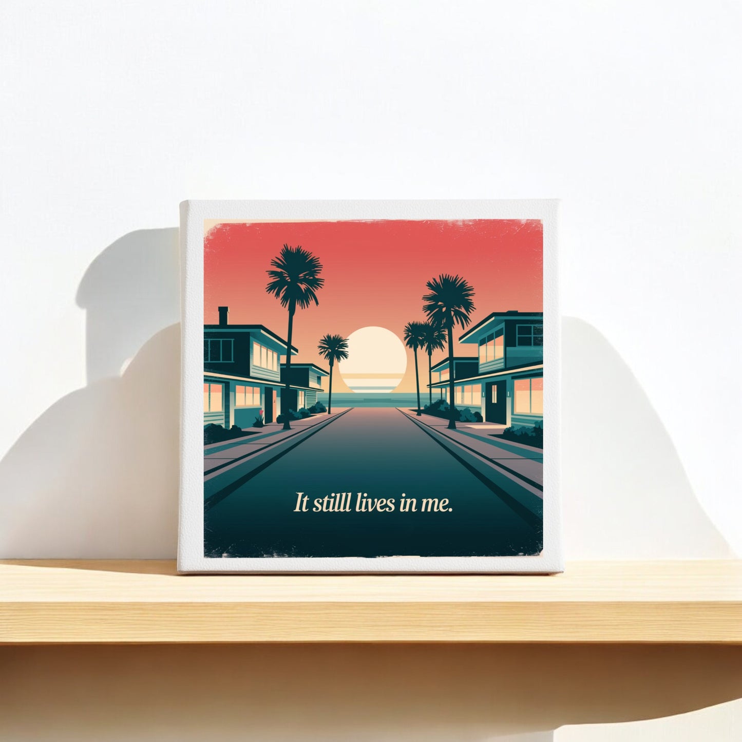 The "It Still Lives in Me Canvas – Retro Sunset Memory Art" by Mirabilia Boutique features a nostalgic sunset between palm-lined buildings with the phrase "It still lives in me," perfect for retro beach decor on any shelf or wall.