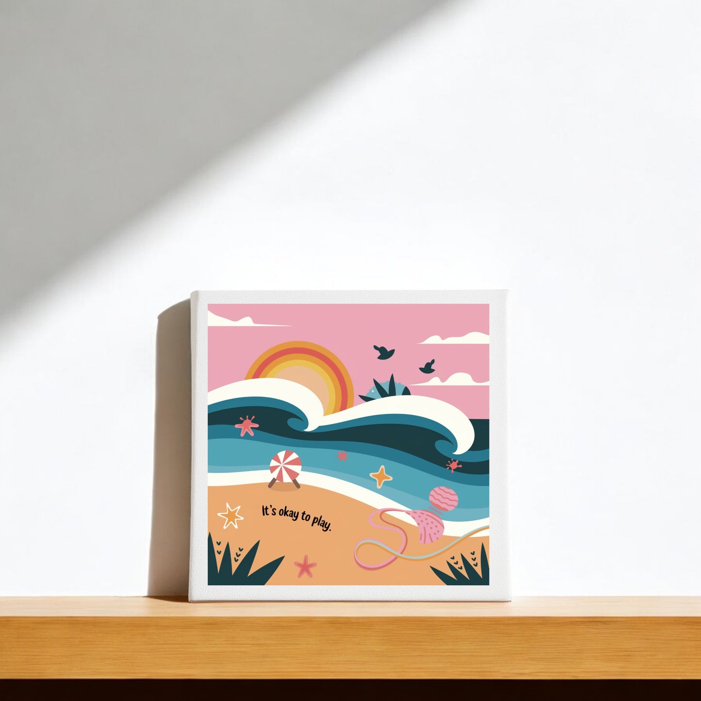 The It’s Okay to Play Canvas – Whimsical Beach Wall Art by Mirabilia Boutique features waves, a sunset, and playful details with “It’s okay to play.” on the bottom—perfect for adding vibrant inspiration to your home decor.