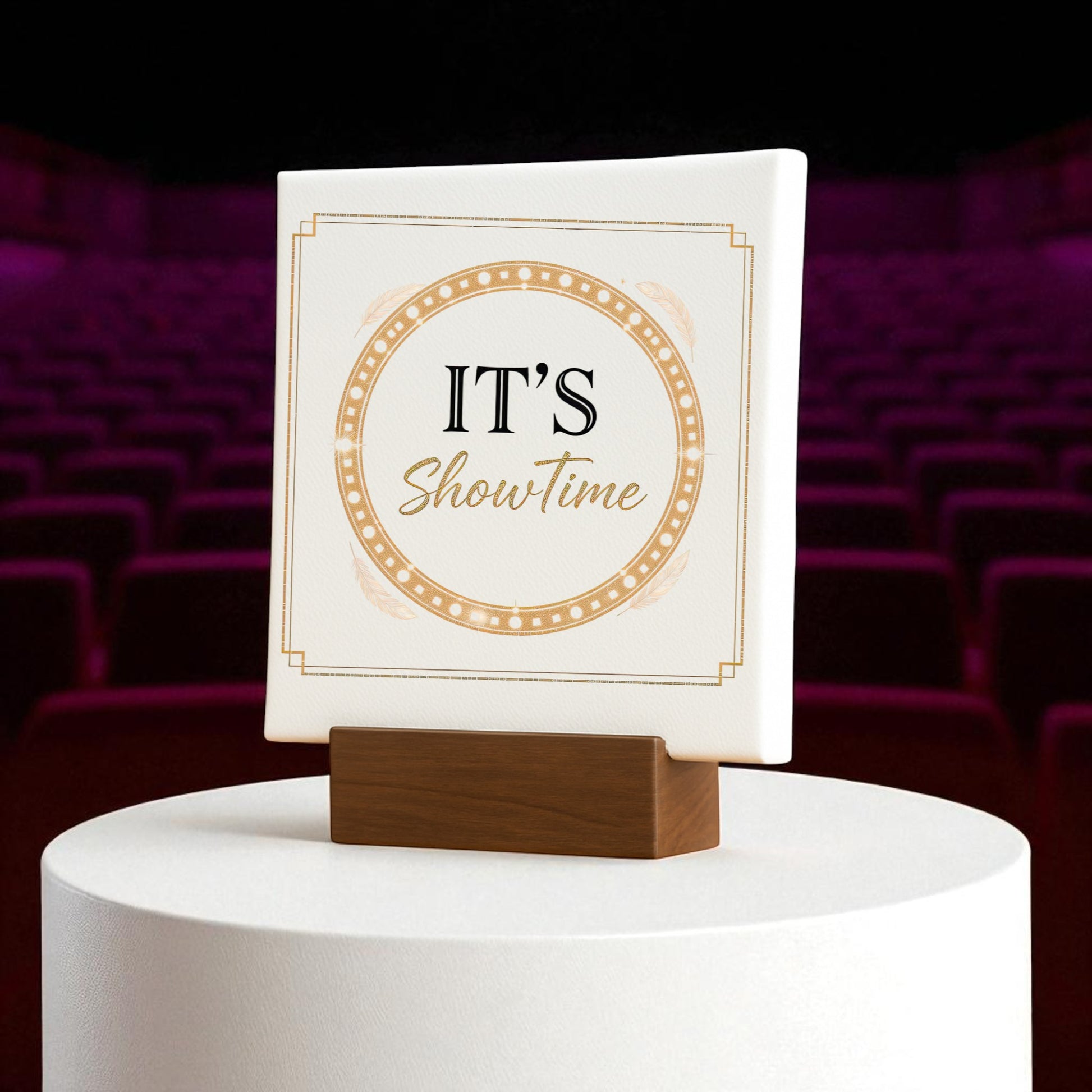 The Mirabilia Boutique “It’s Showtime Mini Sign | Gold Glam Stage Decor” sits on a white pedestal, featuring empty red theater seats and a dramatic backdrop for a Broadway-inspired display.