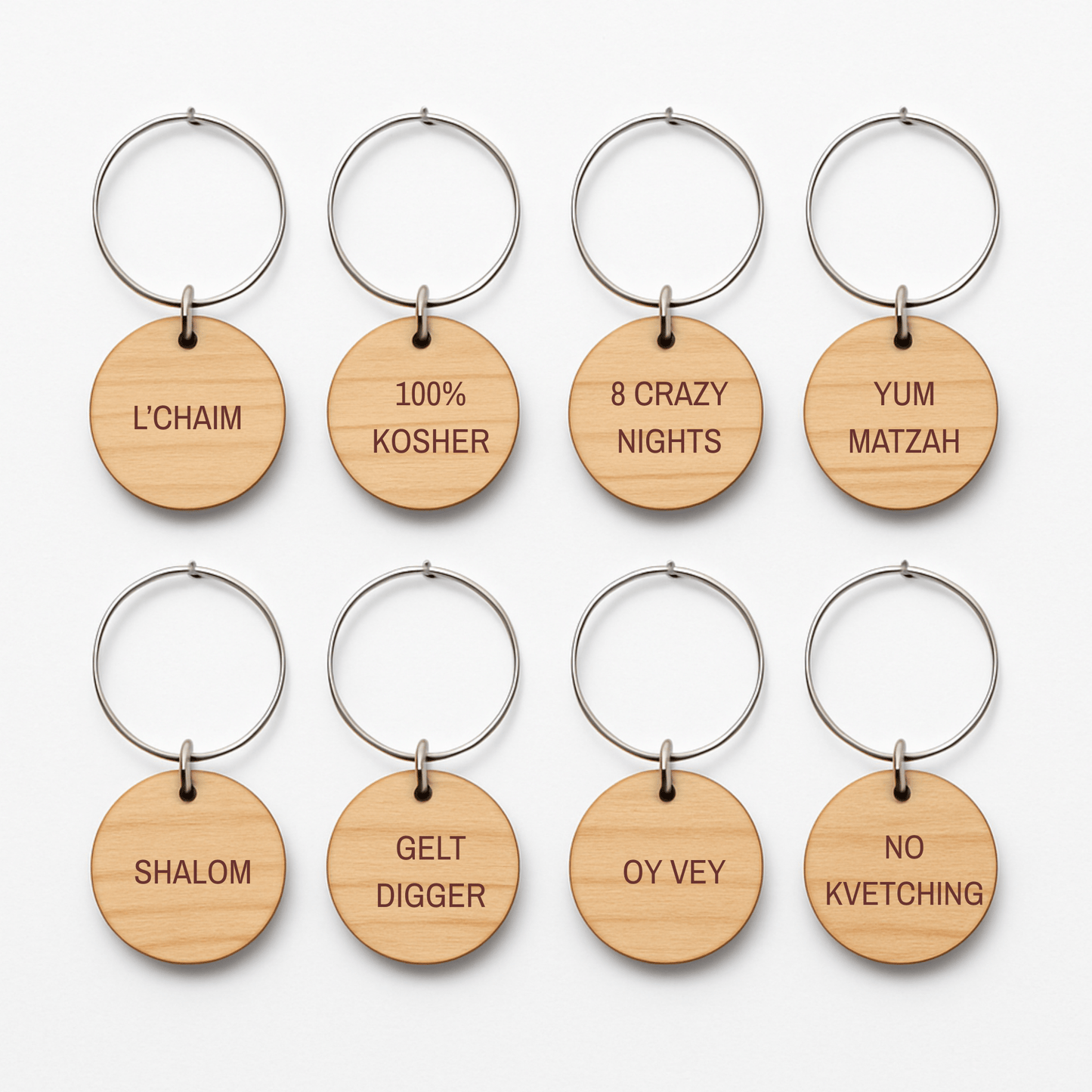 Mirabilia Boutique’s Jewish Wine Charms—Hanukkah Wine Glass Markers Set of 8—feature engraved wooden tags with festive Jewish phrases like “L’CHAIM” and “100% KOSHER,” ideal as holiday gifts or Hanukkah wine charms.