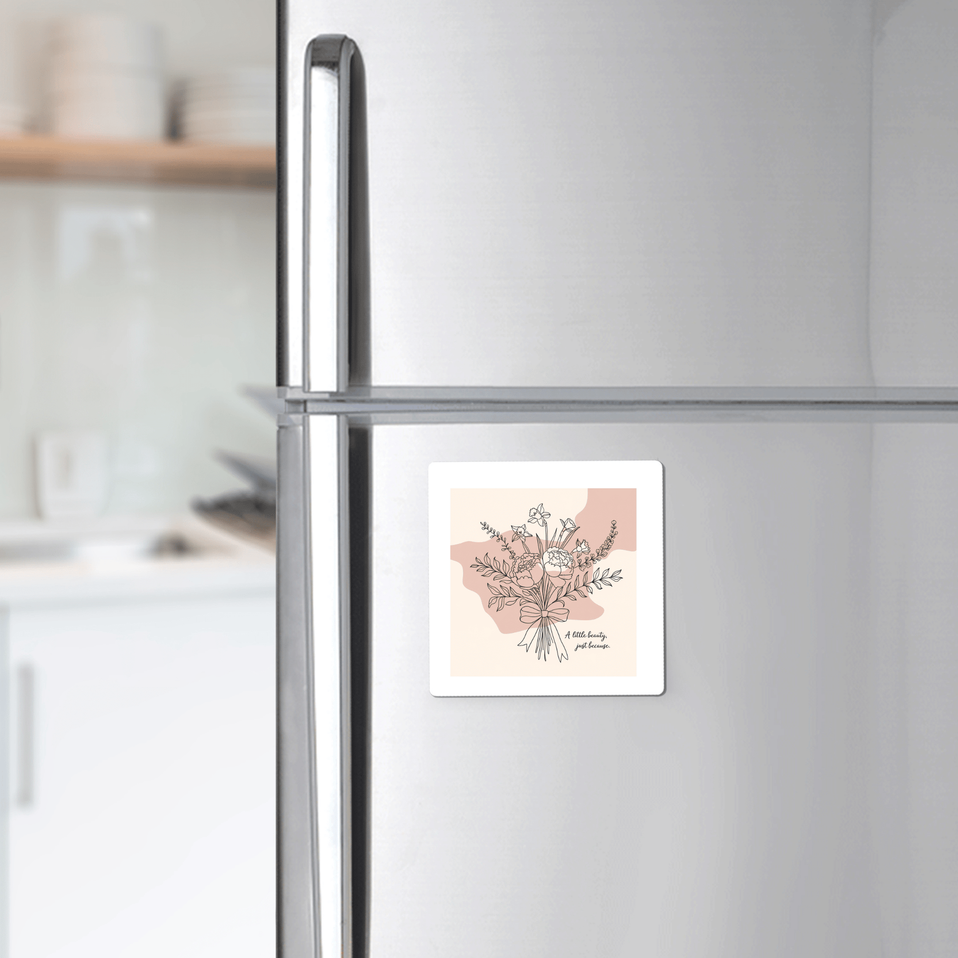 The A Little Beauty Magnet – Just Because Floral Gift by Mirabilia Boutique is shown on a silver fridge in a modern kitchen, making it a charming and thoughtful thinking of you gift.