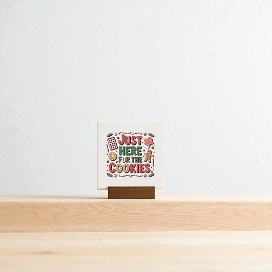 The "Just Here for the Cookies Mini Sign" by Mirabilia Boutique features playful lettering and baking illustrations on a wooden stand, making it a cute Christmas shelf decor or cookie-themed gift. Set against a plain light background.
