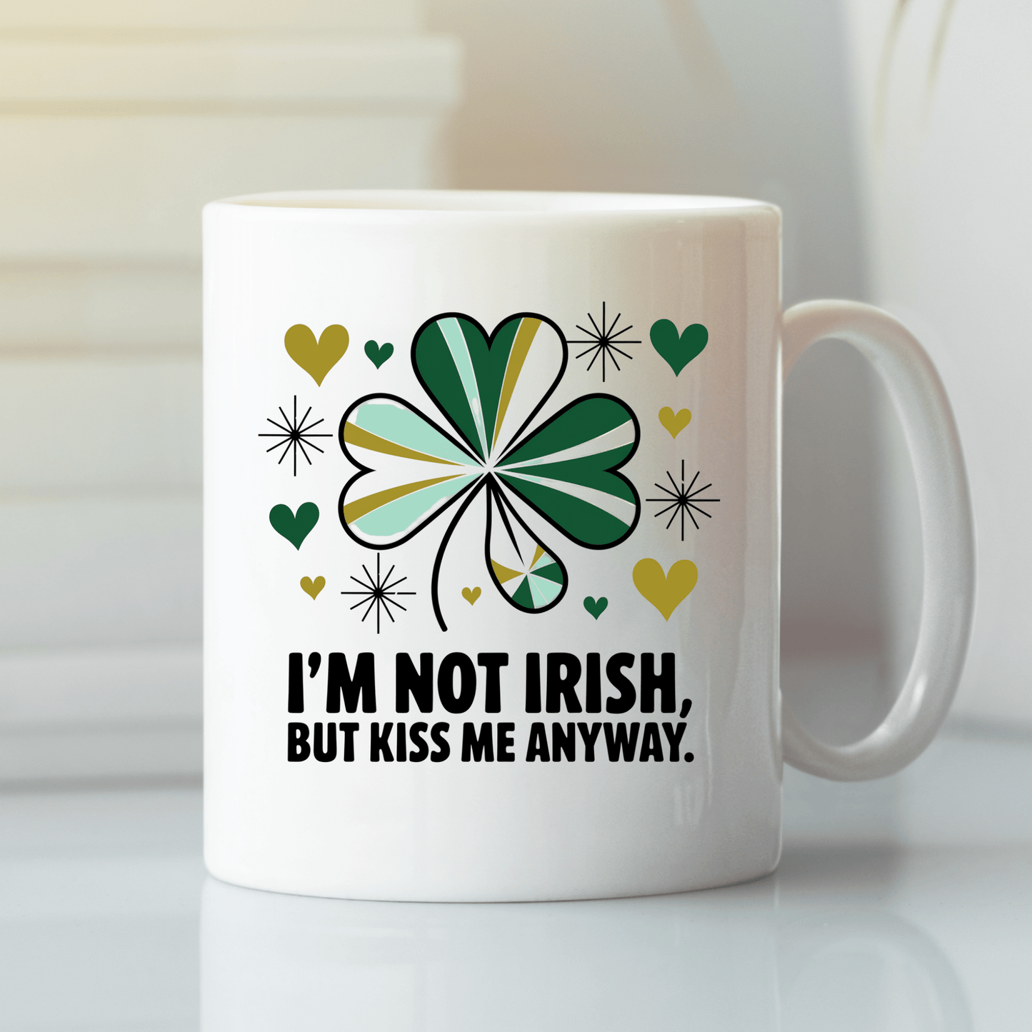 The Kiss Me Anyway Mug – St. Patrick’s Day Charm by Mirabilia Boutique features a green and gold shamrock, hearts, sparkles, and the phrase "I'M NOT IRISH, BUT KISS ME ANYWAY," perfect for festive celebrations.