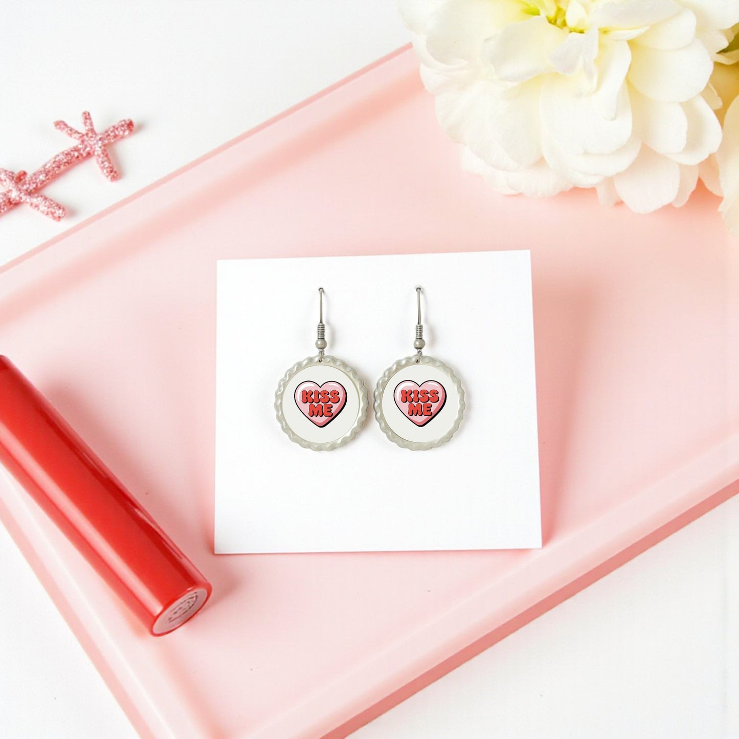 The Kiss Me Heart Earrings by Mirabilia Boutique sit on a white card, making a sweet Valentine’s Day gift jewelry piece for her—perfectly displayed with romantic accents.