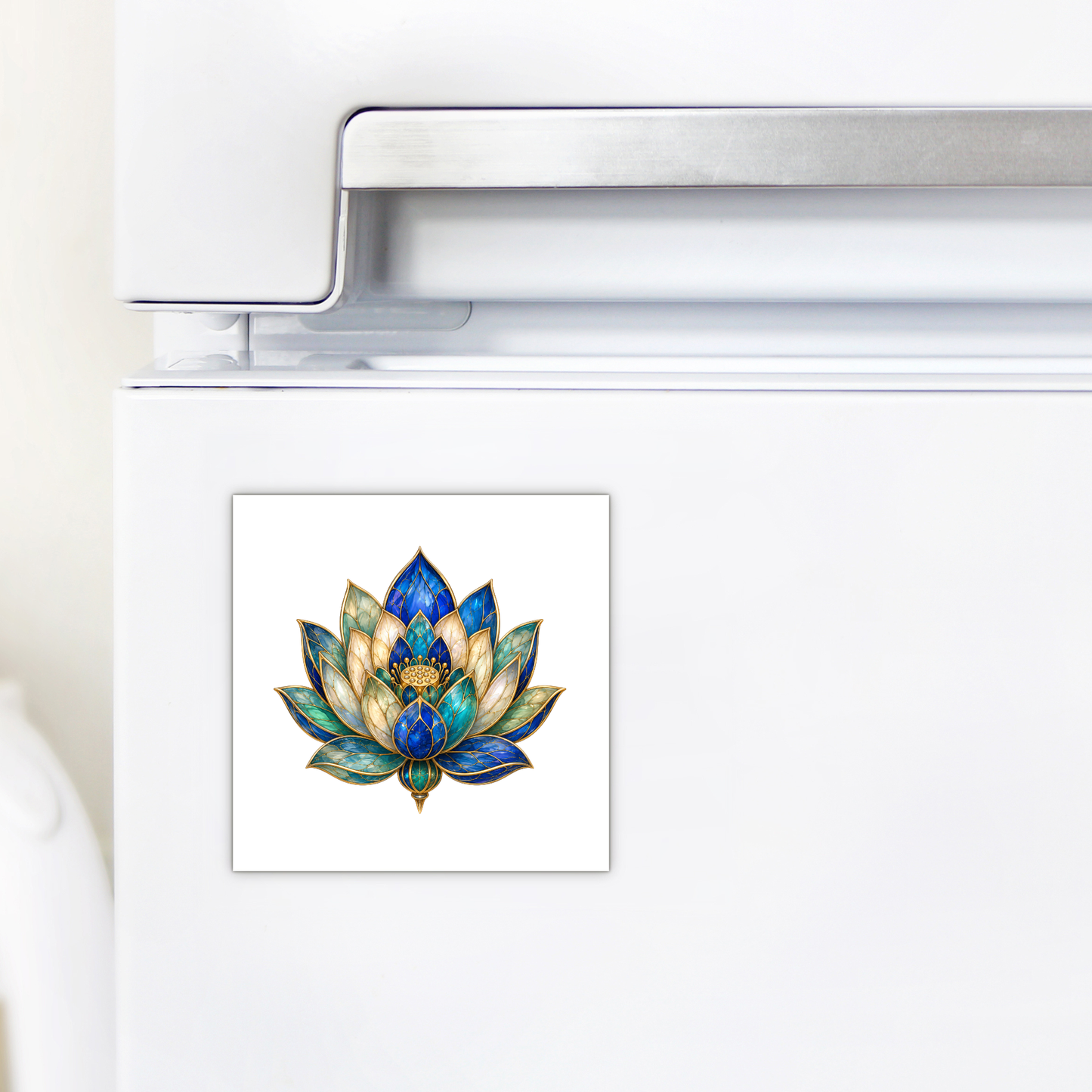 A Lapis Bloom Magnet from Mirabilia Boutique, featuring Egyptian lotus art in striking blue and gold hues, decorates the white refrigerator door near the handle.