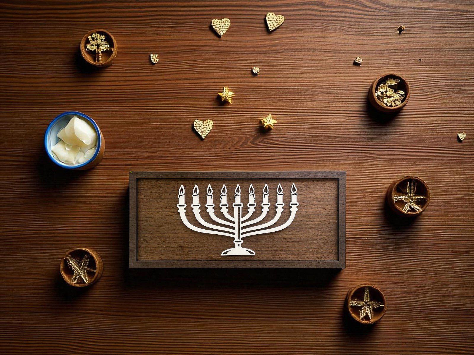 The Minimalist Menorah Decor | 9x4 Laser Cut Hanukkah Sign by Mirabilia Boutique sits on a wooden table, surrounded by gold-decorated bowls, a blue bowl of white cubes, and gold hearts—perfect for modern Hanukkah celebrations.