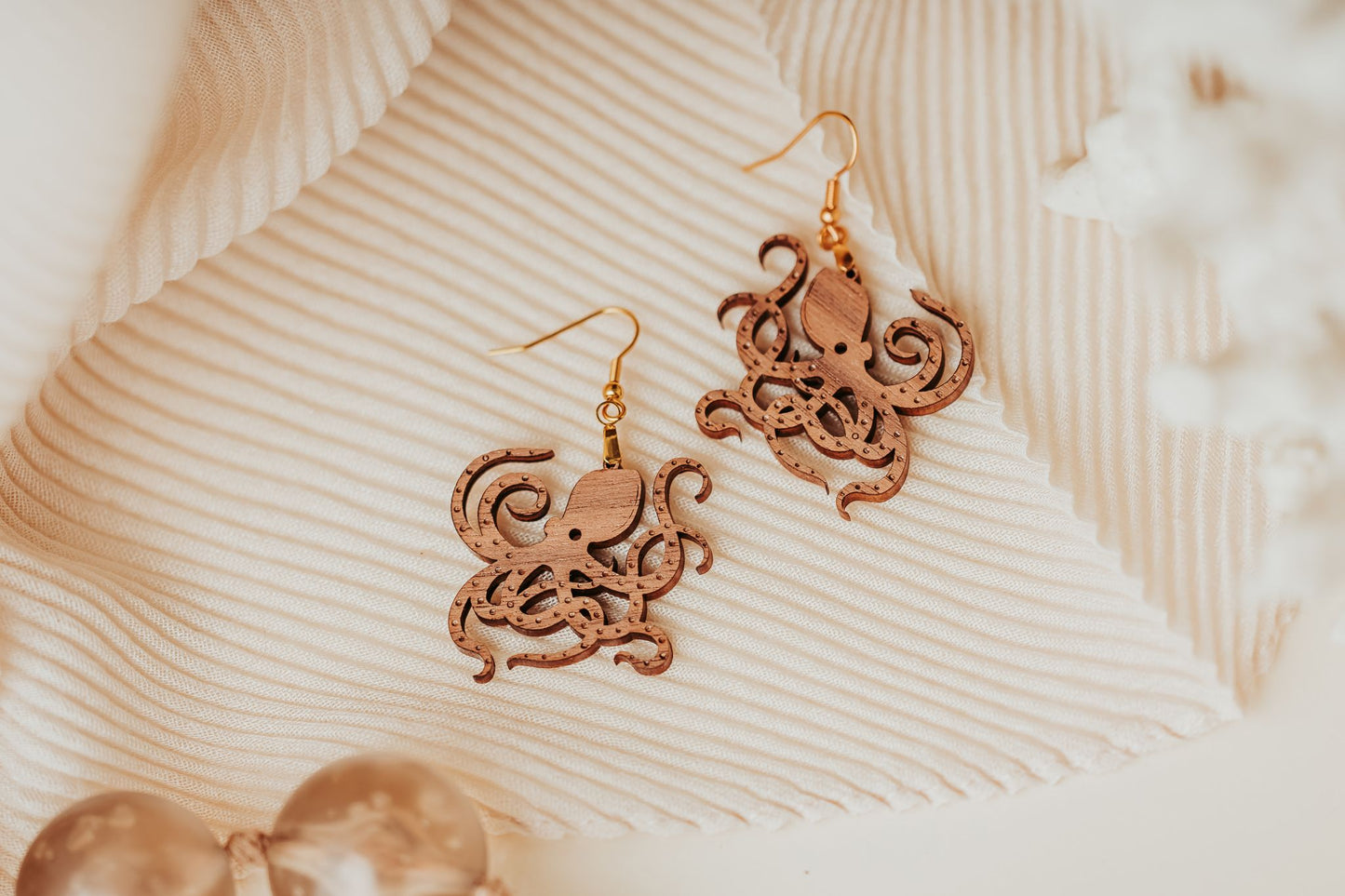 Mirabilia Boutique’s Octopus Earrings—laser cut wood ocean jewelry with gold hooks—make an elegant gift for nature or sea life lovers, beautifully displayed on cream fabric.