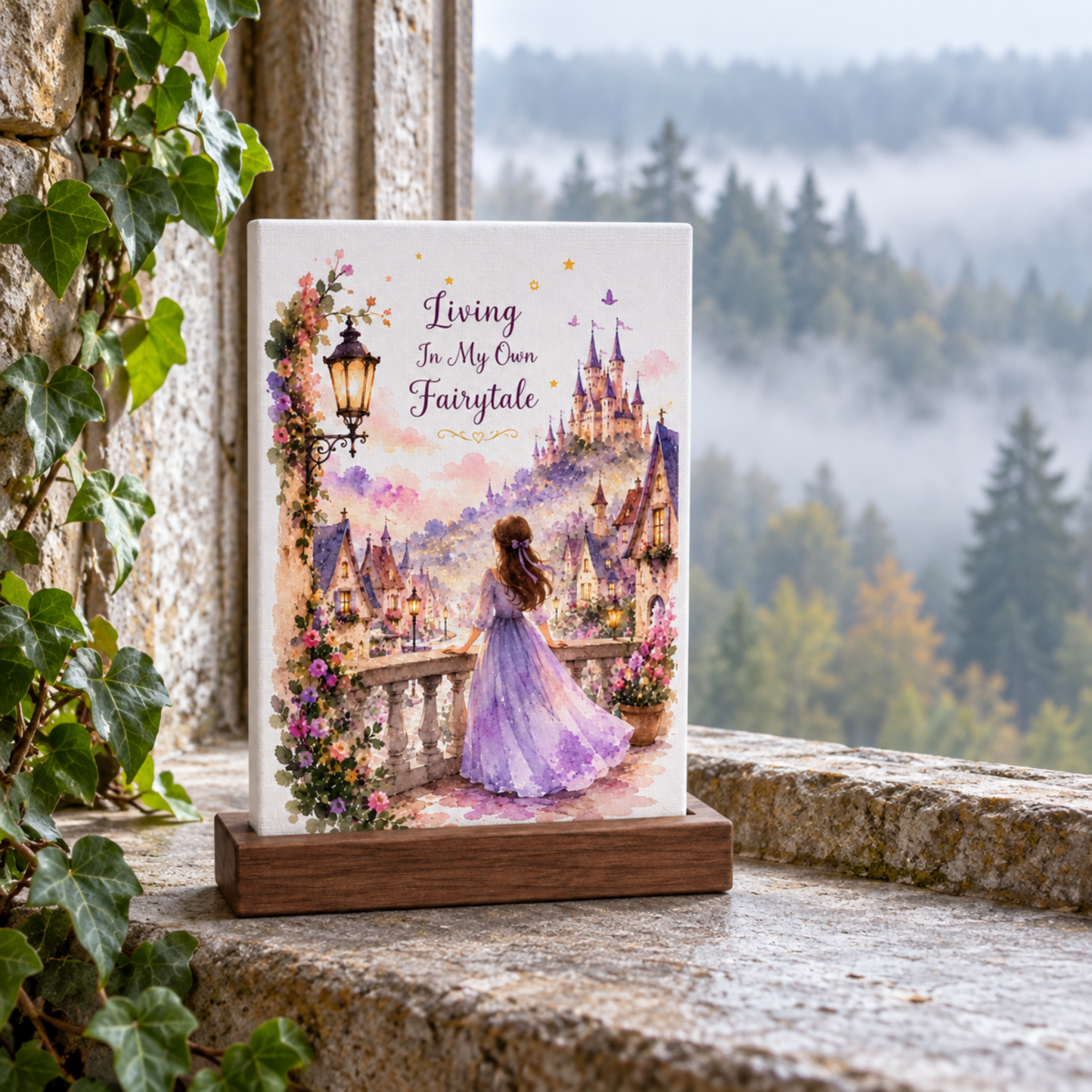 A Living in My Own Fairytale Mini Canvas on a wooden stand depicts a woman in a gown looking toward a castle, with the text “Living In My Own Fairytale” written above her.