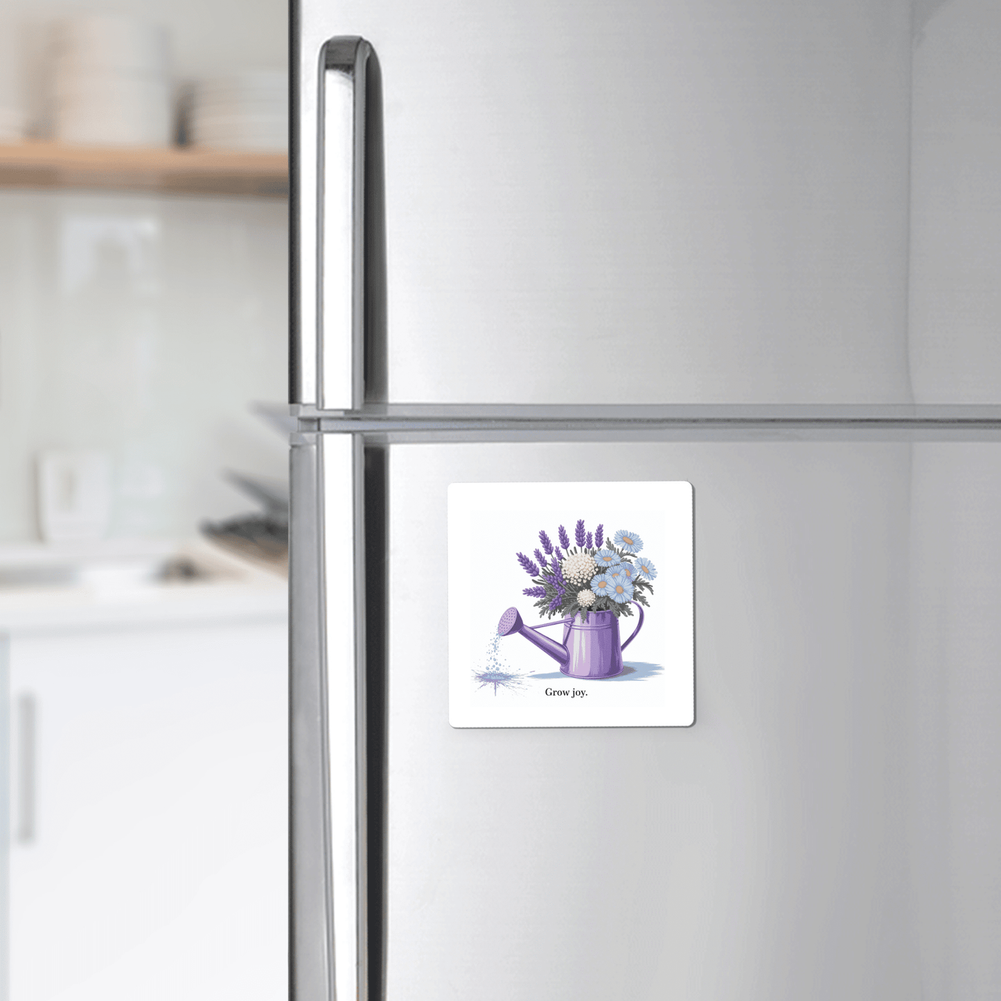 A silver fridge displays the Mirabilia Boutique Grow Joy Magnet, featuring a square design with a watercolor watering can and soft garden florals. The magnet reads "Give joy"—a perfect floral kitchen decor piece or a gift for gardeners.