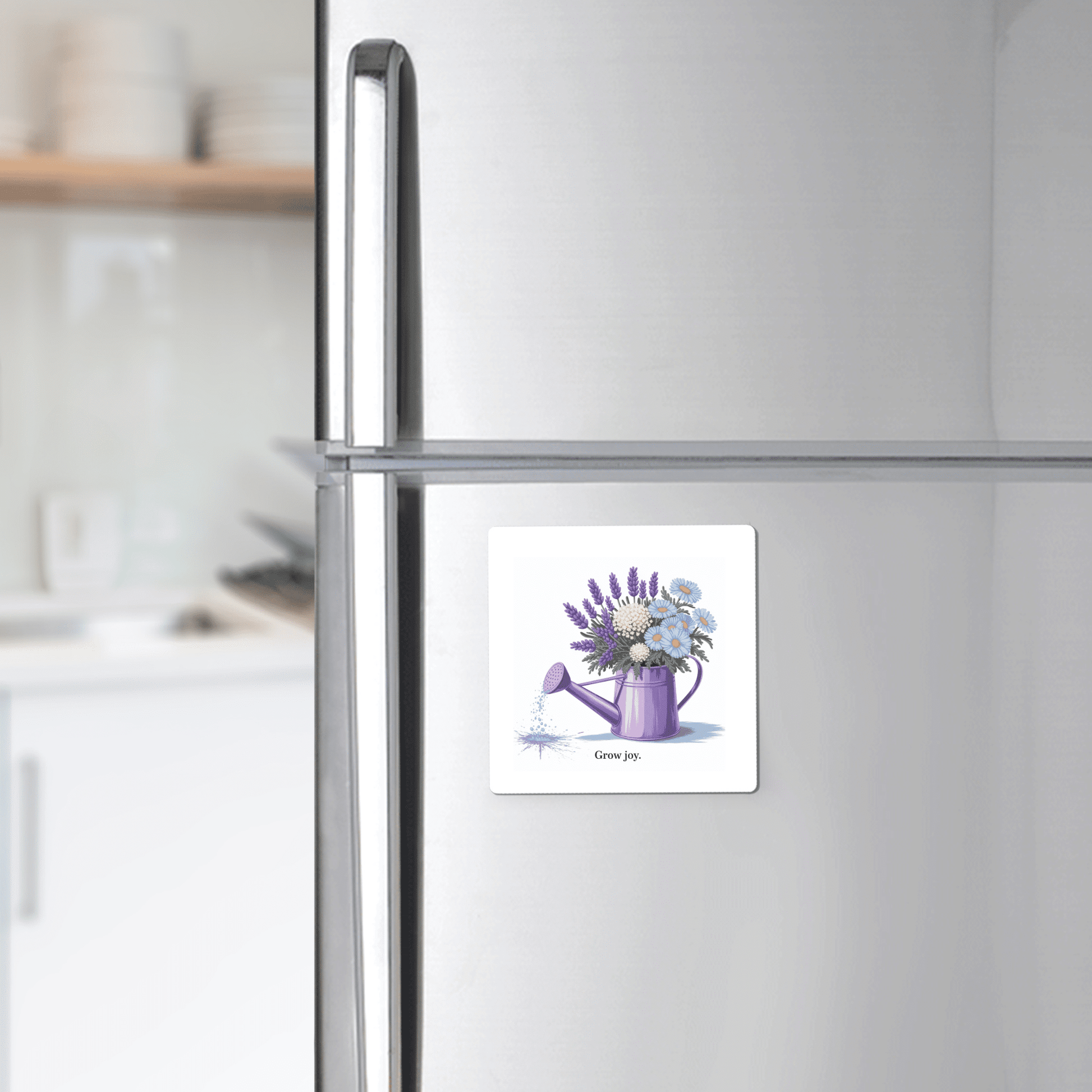 A silver fridge displays the Mirabilia Boutique Grow Joy Magnet, featuring a square design with a watercolor watering can and soft garden florals. The magnet reads "Give joy"—a perfect floral kitchen decor piece or a gift for gardeners.