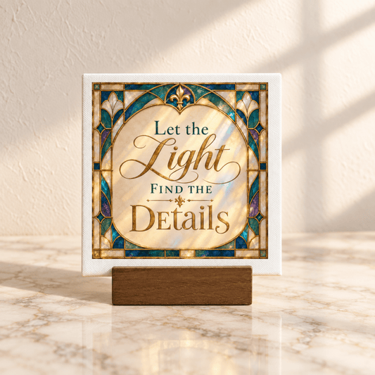 The Let the Light Find the Details Mini Sign by Mirabilia Boutique features an art nouveau stained glass design and sits on a wooden stand placed on a marble surface, set against a light-colored textured wall.