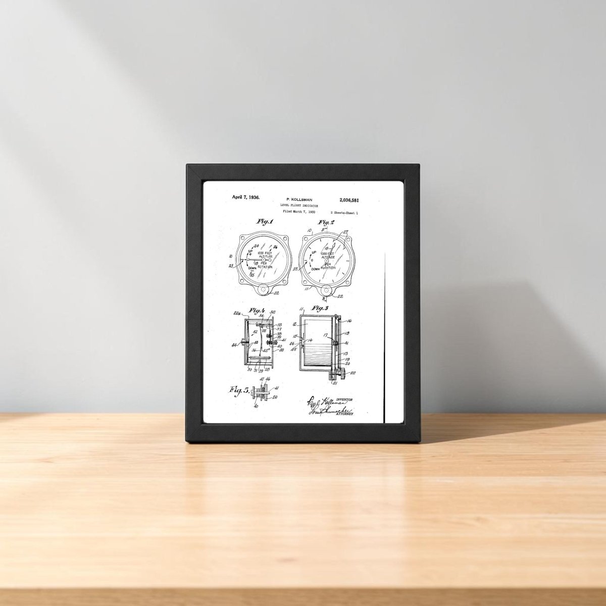 The Level Flight Indicator Patent Art Print by Mirabilia Boutique rests on a light wooden surface against a plain gray wall, showcasing detailed aviation diagrams—ideal decor for engineering enthusiasts.