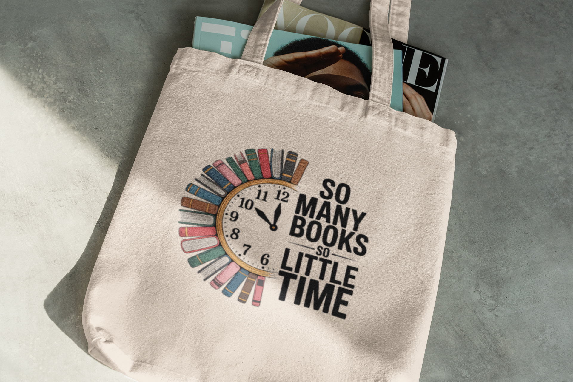 The So Many Books Canvas Tote Bag by Mirabilia Boutique features a clock and colorful books with "So many books so little time." Ideal as a book lover’s gift or library tote, it’s pictured on a gray surface with a magazine peeking out.