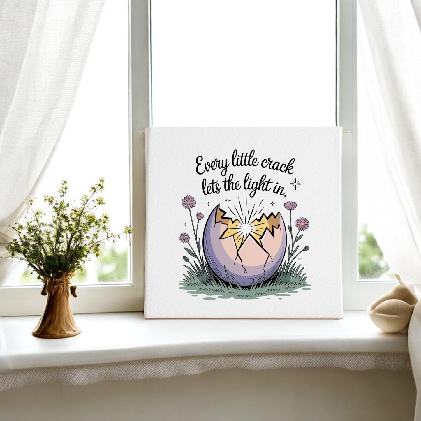 The "Every Little Crack Lets the Light In Canvas Art" by Mirabilia Boutique features a cracked egg on a windowsill with light shining through, wildflowers, and the inspiring quote above—perfect for uplifting wall decor.