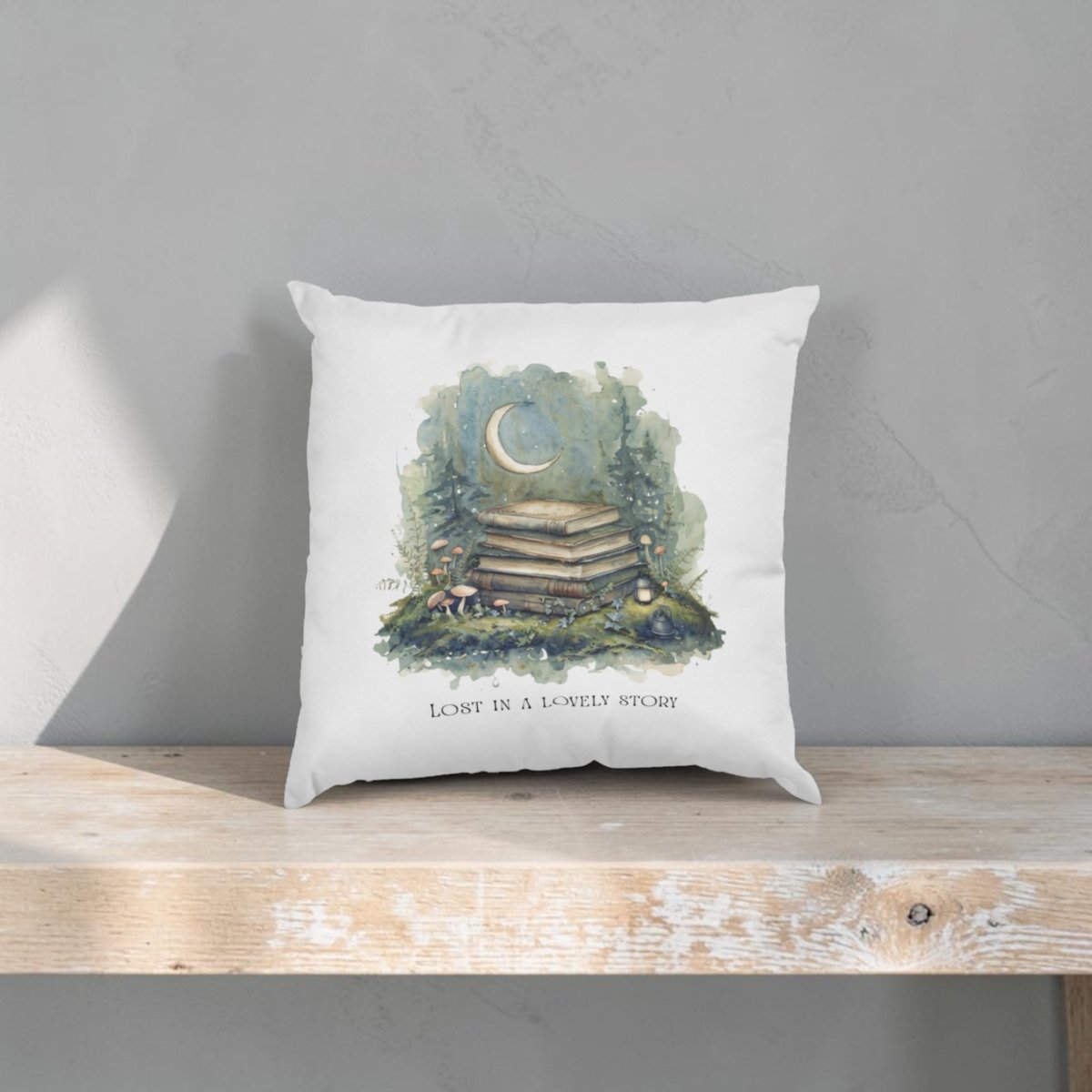 The "Lost in a Lovely Story Throw Pillow" by Mirabilia Boutique rests on a wooden shelf, showcasing an enchanting illustration of books, a crescent moon, mushrooms, and string lights above the phrase "Lost in a lovely story"—an ideal piece for cozy cottagecore decor or to bring charm to any reading nook.