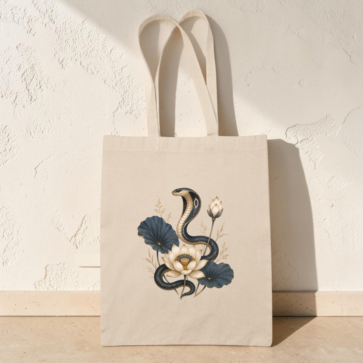 Elevate your everyday style with the Lotus Guardian Cobra Tote Bag from Mirabilia Boutique—this beige tote features ancient Egyptian art of a black cobra surrounded by white and blue flowers, creating an elegant and exotic accessory.