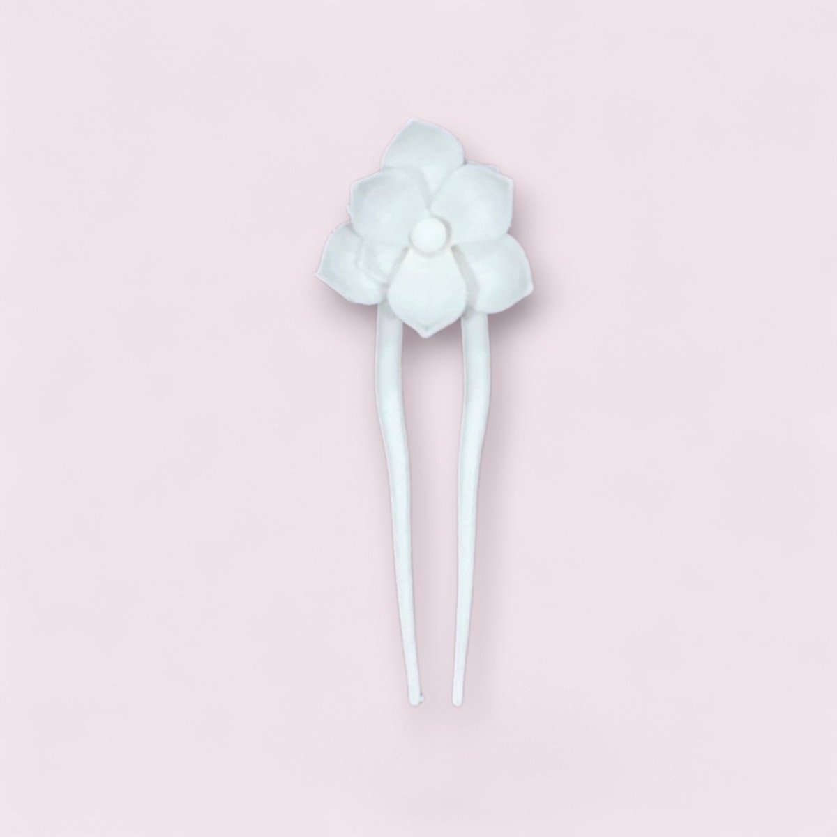 The Lotus Hair Fork in Matte Cotton White by Mirabilia Boutique is a decorative accessory with a flower-shaped ornament and two prongs, beautifully showcased on a light pink background.