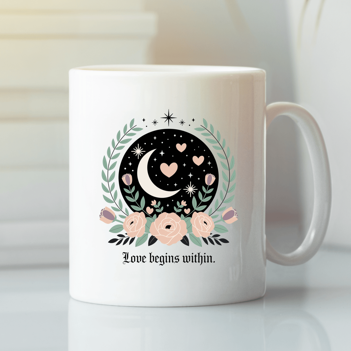 The Love Begins Within Mug by Mirabilia Boutique features a white design with a crescent moon, hearts, stars, flowers, and leaves, plus the quote “Love begins within.” A mindful self-love gift for any occasion.