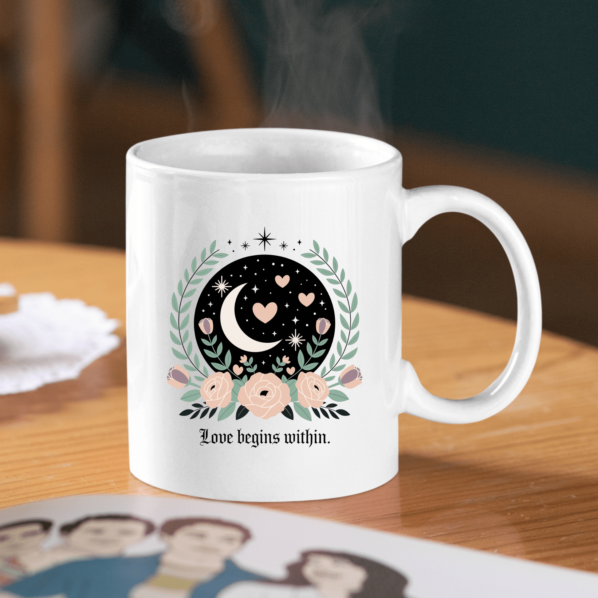 The Love Begins Within Mug by Mirabilia Boutique features moon and floral art, plus the phrase “Love begins within” on the bottom—a mindful self-love gift, perfect for inspiring moments over coffee or tea.