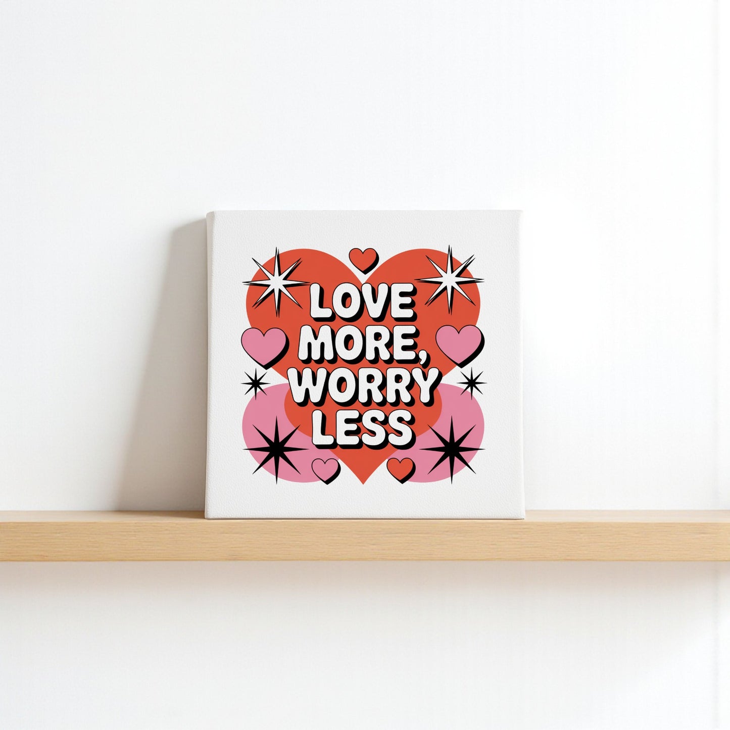 The Mirabilia Boutique Love More Worry Less Canvas (8x8) features bold text, red and pink hearts, and starbursts—a perfect square midcentury wall art to add charm to any plain white wall.