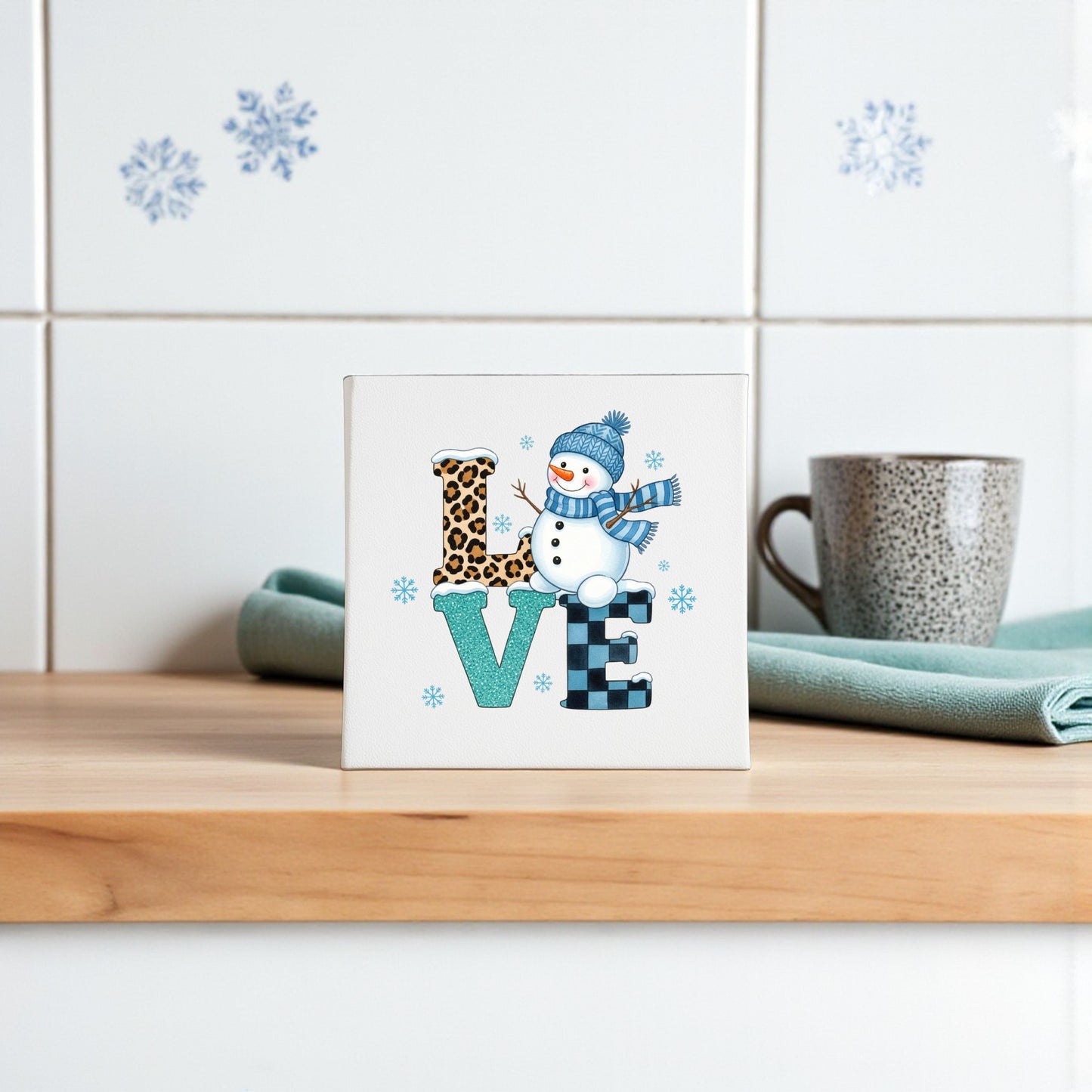 The LOVE Snowman Canvas Sign by Mirabilia Boutique spells "LOVE" with unique patterns and a snowman for the “O,” making it ideal winter and Valentine’s decor for your home. A stylish accent on any counter or shelf!.