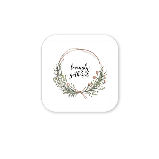 The Lovingly Gathered Magnet – Floral Wreath Quote for Fridge by Mirabilia Boutique features green leaves and pink flowers encircling “lovingly gathered” in script, making it a charming farmhouse decor accent for your kitchen.