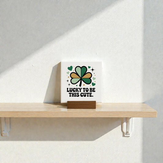 The Lucky to Be This Cute Canvas Sign – 4x4 by Mirabilia Boutique features green, black, and gold shamrocks and hearts with the phrase "Lucky to be this cute." Ideal clover decor or St. Patrick’s Day gift for shelves or nurseries.