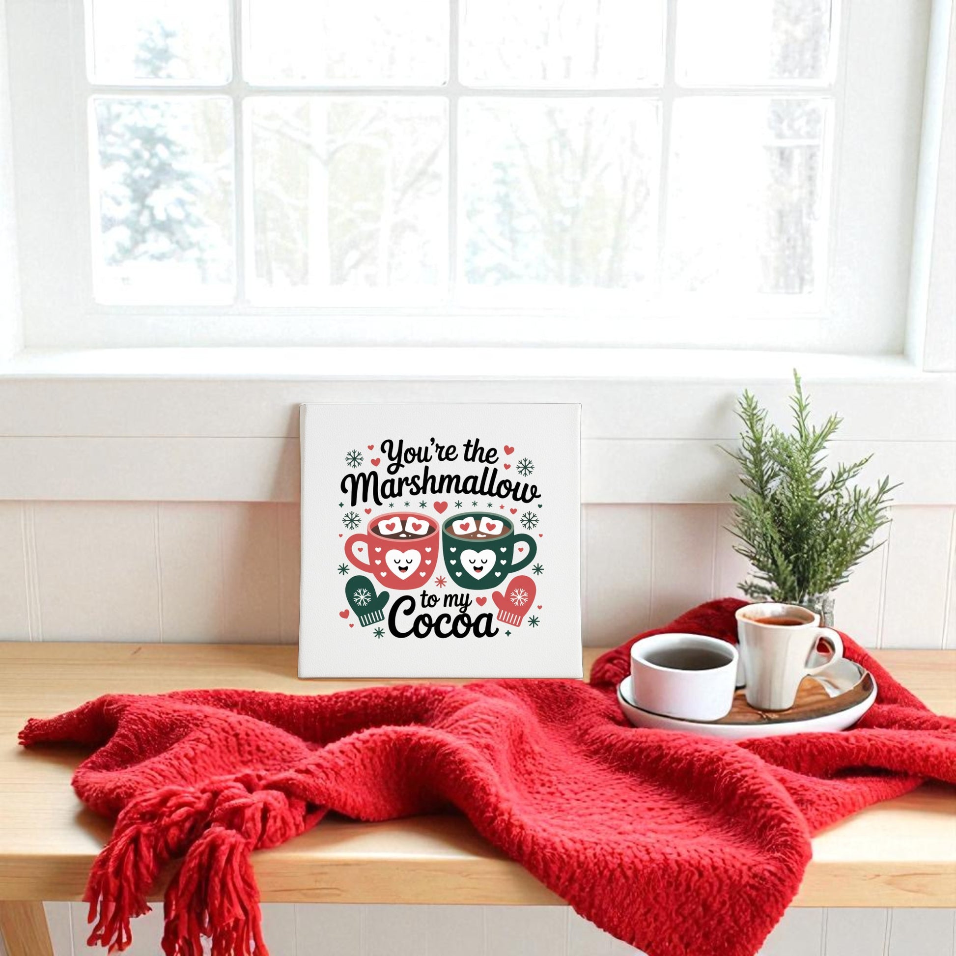 Create a cozy winter vibe with the Marshmallow to My Cocoa Sign by Mirabilia Boutique. This 8x8 canvas art pairs perfectly with a red blanket, coffee, and snowy trees for a charming seasonal touch.
