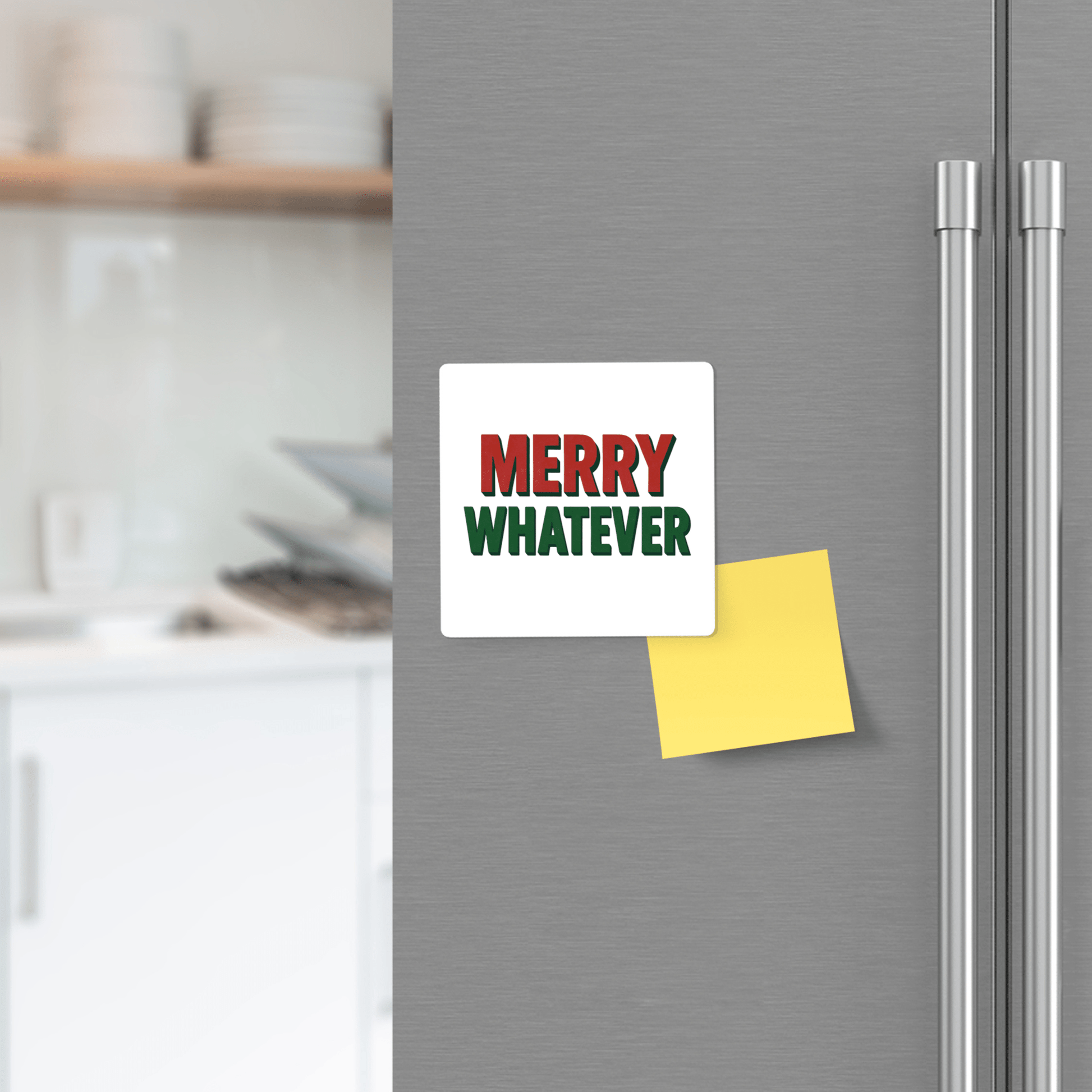 The Merry Whatever Magnet by Mirabilia Boutique, a funny minimalist Christmas gift, is displayed on a fridge door beside a blank yellow sticky note with a blurred kitchen background.