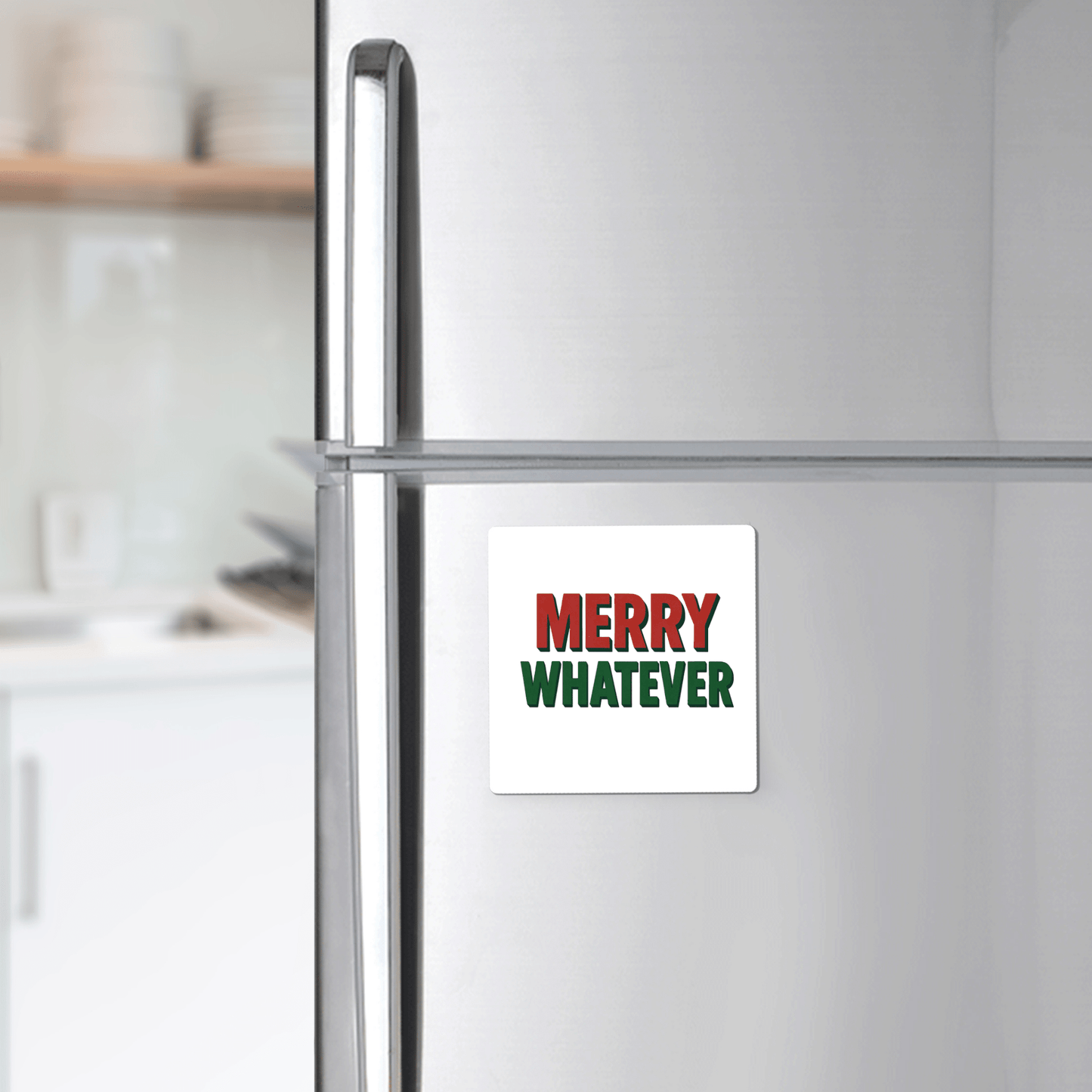 A silver fridge displays the Mirabilia Boutique "Merry Whatever Magnet," a square, minimalist holiday gift with red and green lettering—an ideal sarcastic Christmas present or stocking stuffer. Bright kitchen shelves appear in the background.