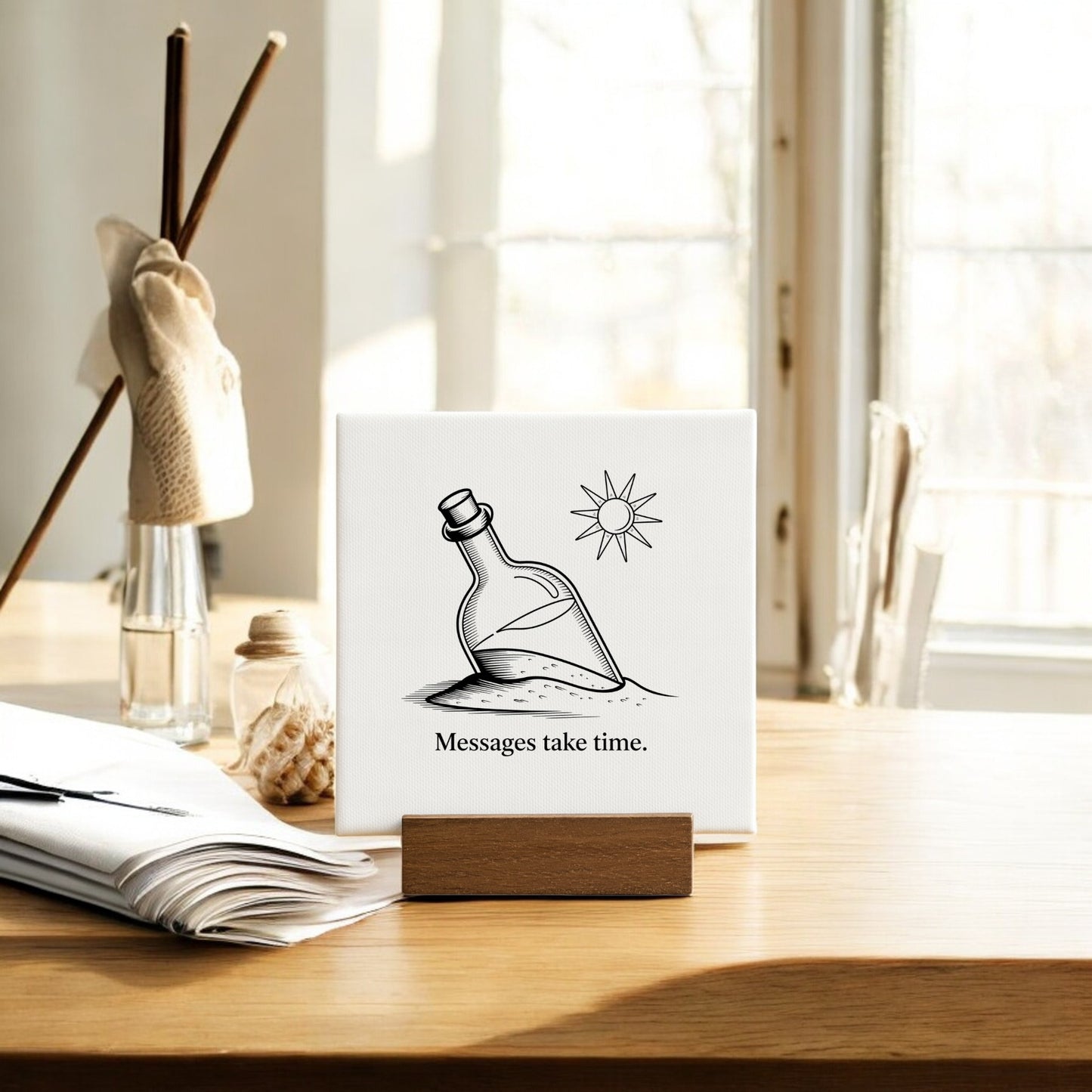 The Mirabilia Boutique Messages Take Time Mini Canvas – Desk Art with Wood Stand features a "message in a bottle" design drawn in sand under the sun, paired with the phrase "Messages take time." Perfect for bright desks or shelves.
