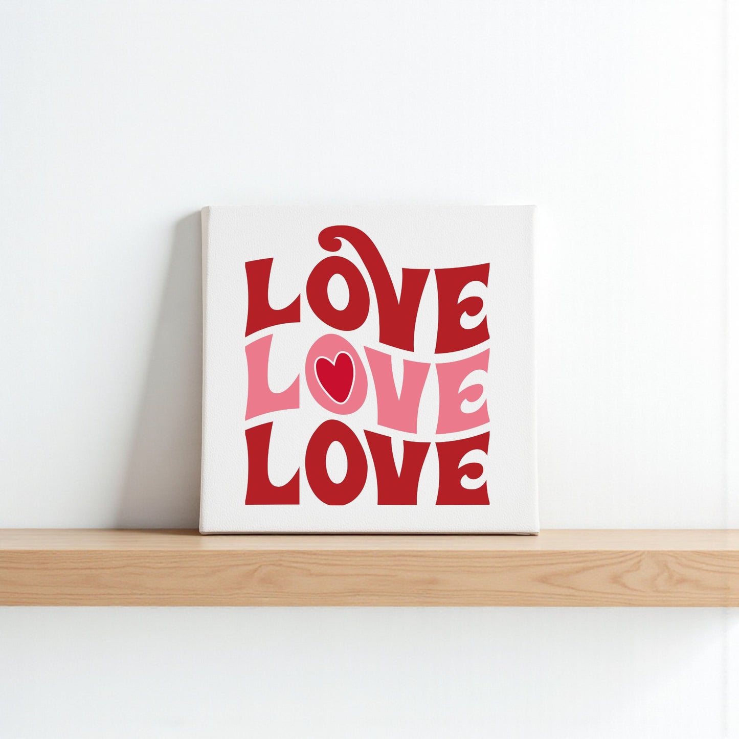 The Retro LOVE Canvas by Mirabilia Boutique features "LOVE" in bold, wavy red and pink retro letters with a heart in the "O." This groovy wall art is perfect Valentine’s Day decor for any space.