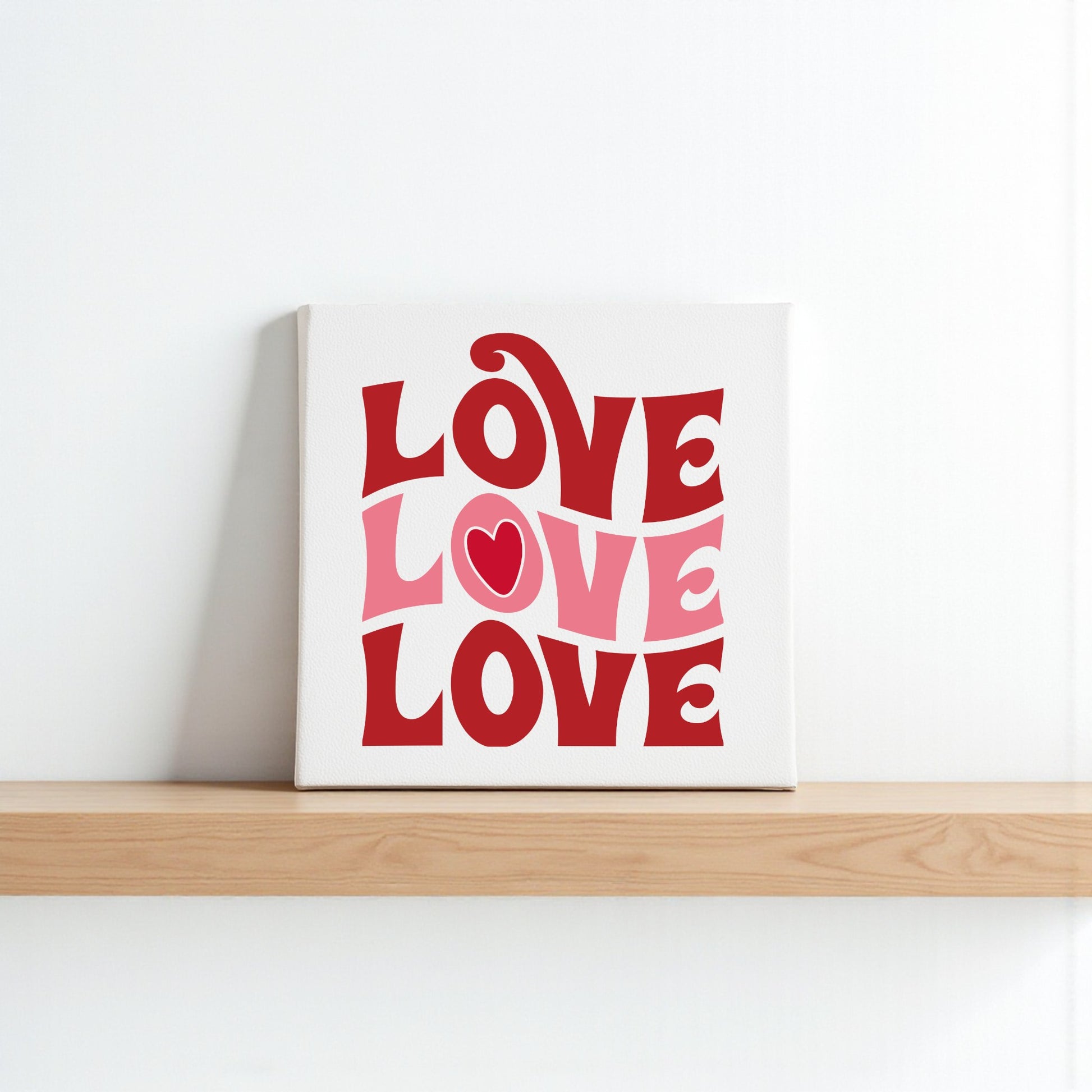 The Retro LOVE Canvas by Mirabilia Boutique features "LOVE" in bold, wavy red and pink retro letters with a heart in the "O." This groovy wall art is perfect Valentine’s Day decor for any space.