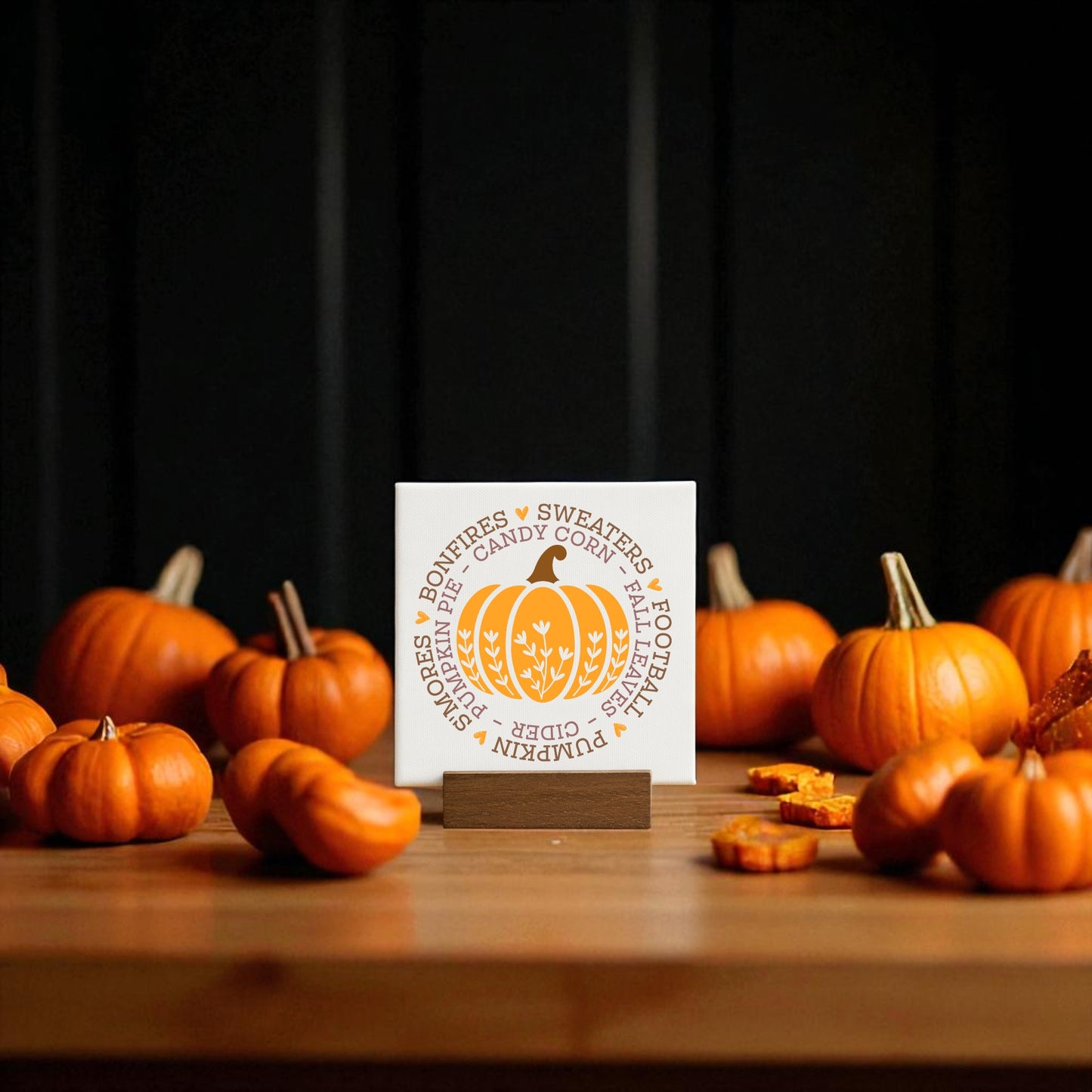The Mini Fall Sign by Mirabilia Boutique features autumn words and pumpkin art on a square card, displayed on a wooden holder with pumpkin decor—perfect for cozy seasonal gifting.