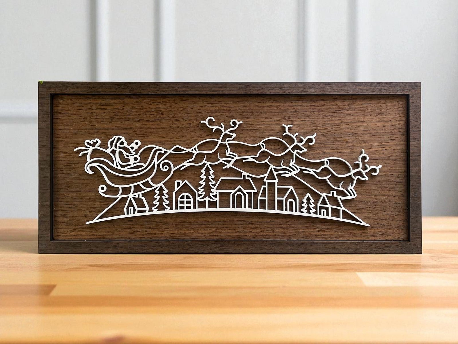 The Mirabilia Boutique Rustic Santa Sleigh Sign (18x8) features a minimalist white Santa and reindeer outline over a village—perfect for Scandinavian Christmas or rustic holiday decor.