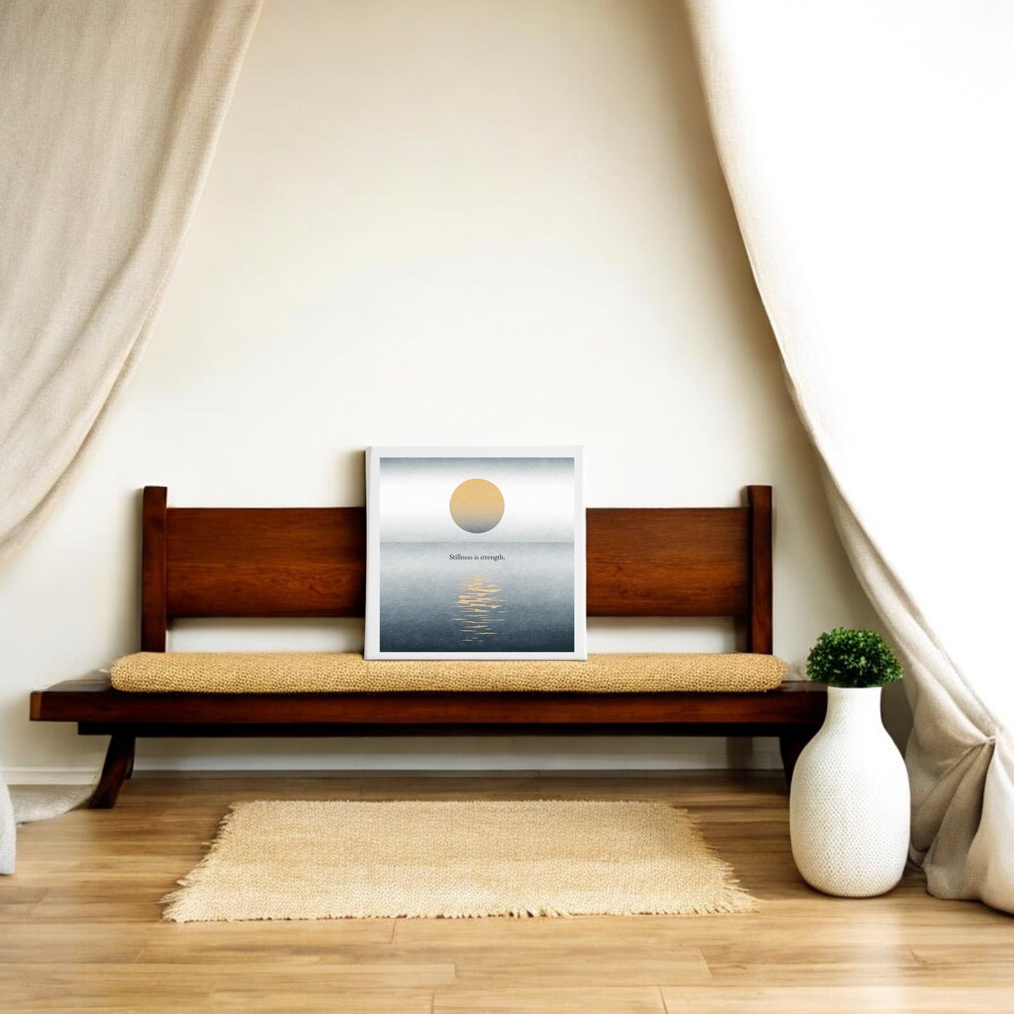 A minimalist room with a wooden bench, beige cushion, Mirabilia Boutique’s "Stillness Is Strength" Canvas Wall Art, cream curtains, woven rug, and a white vase with greenery—perfect tranquil meditation decor.