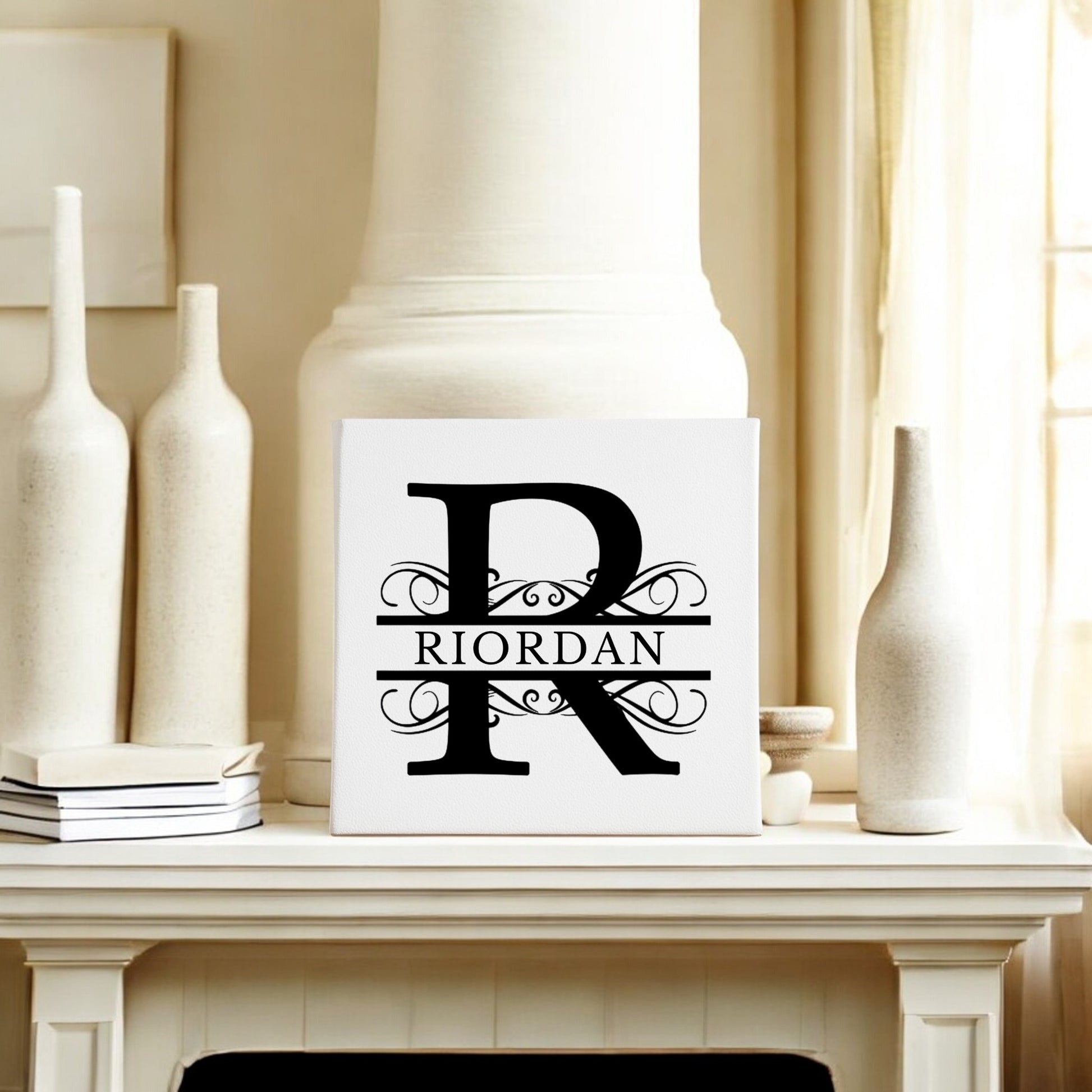 A white mantel showcases Mirabilia Boutique’s Custom Monogram Canvas with Family Name – 8x8, featuring a bold black "R," ornate swirls, and "RIORDAN" across the center for an elegant personalized wall art display.