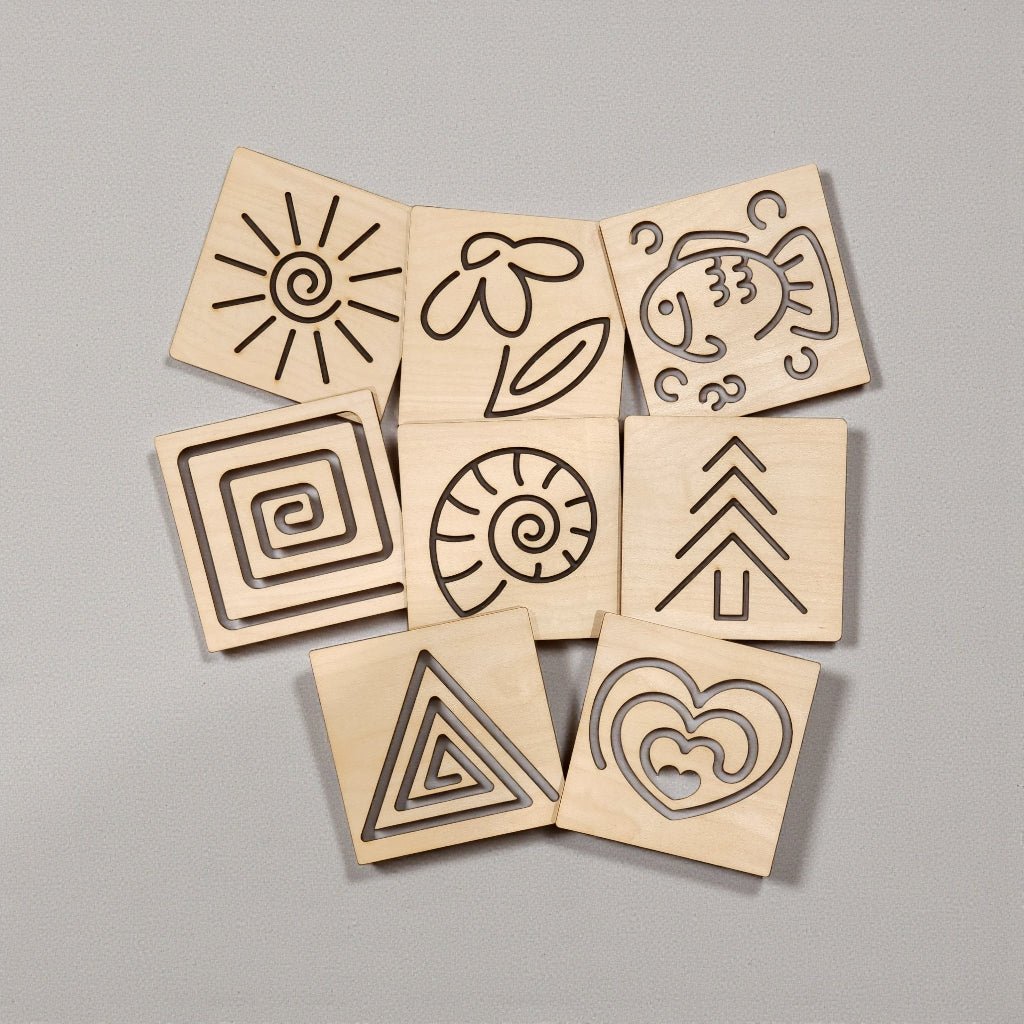 The Mirabilia Boutique Montessori Style Tracing Boards Set of 8 features engraved sun, flower, fish, swirl, spiral, tree, triangle, and hearts designs to foster pre-writing skills and fine motor control.