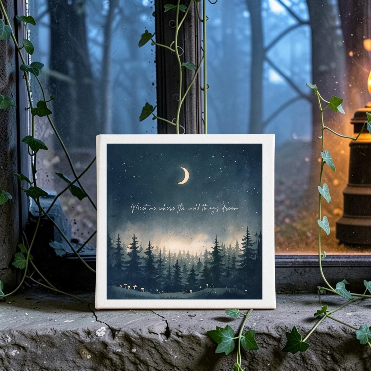 The Meet Me Where the Wild Things Dream Canvas by Mirabilia Boutique features a square design with a dreamy forest scene, crescent moon, and twinkling stars—perfect as celestial home decor. Displayed on a windowsill amidst trailing ivy, this enchanting woodland decor piece showcases the inspirational quote, "Meet me where the wild things dream." A lantern glows in the misty moonlit woods outside, making it an atmospheric accent for any space.