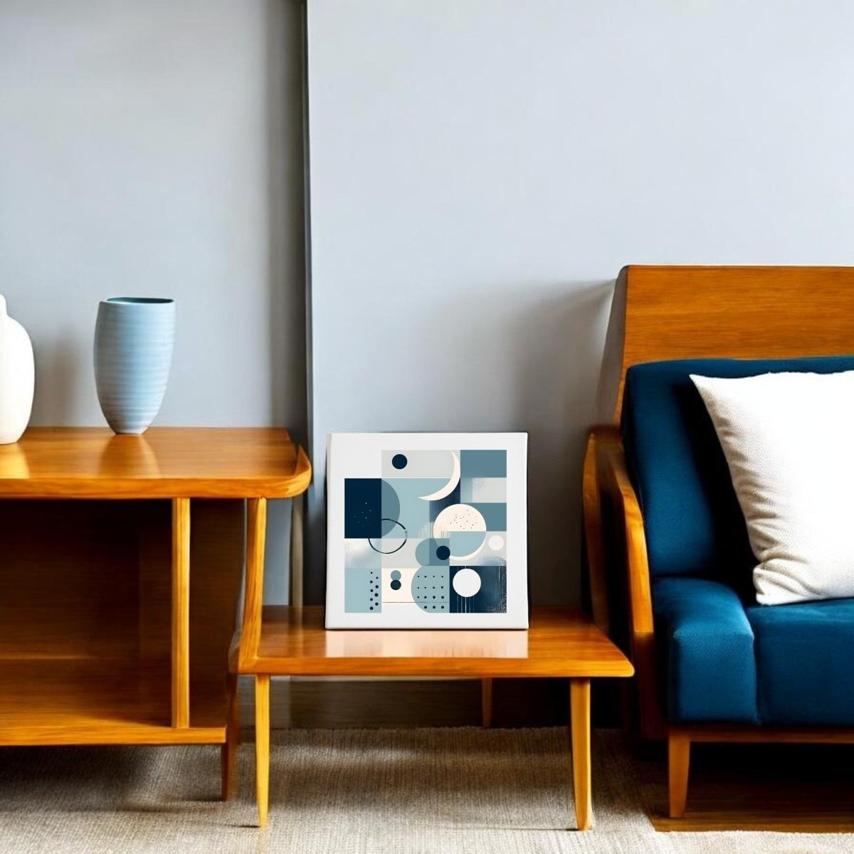 A modern living room with wooden side and coffee tables, a blue-cushioned sofa, and a Moonlit Geometry Mid Century Modern Canvas by Mirabilia Boutique. A blue vase decorates the table against a plain gray wall.