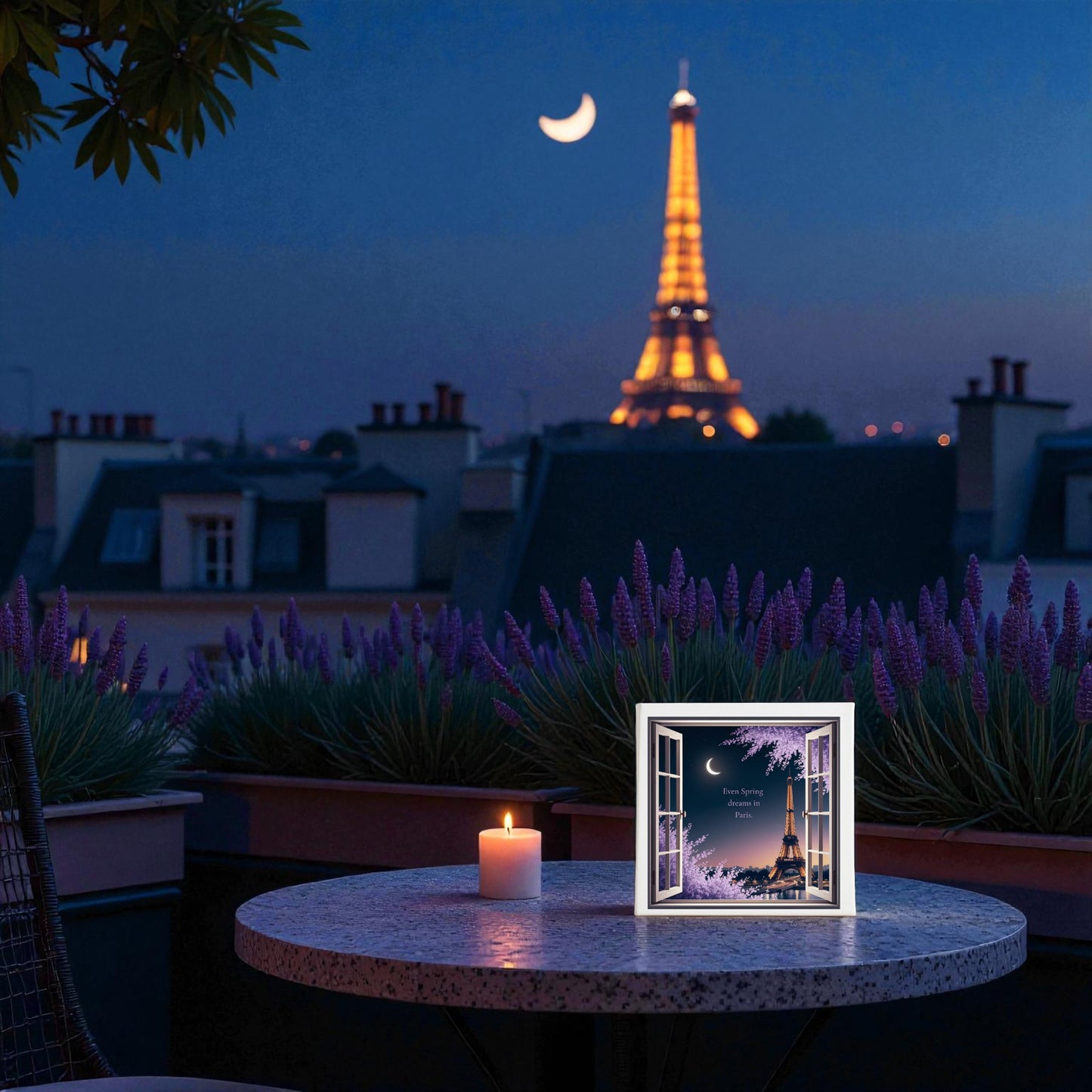 A round table on a terrace at night holds a candle and framed Eiffel Tower photo, surrounded by flowers and rooftops, with the glowing tower beyond—ideal for your Mirabilia Boutique Spring Dreams in Paris Canvas – Moonlit Eiffel Tower Art.