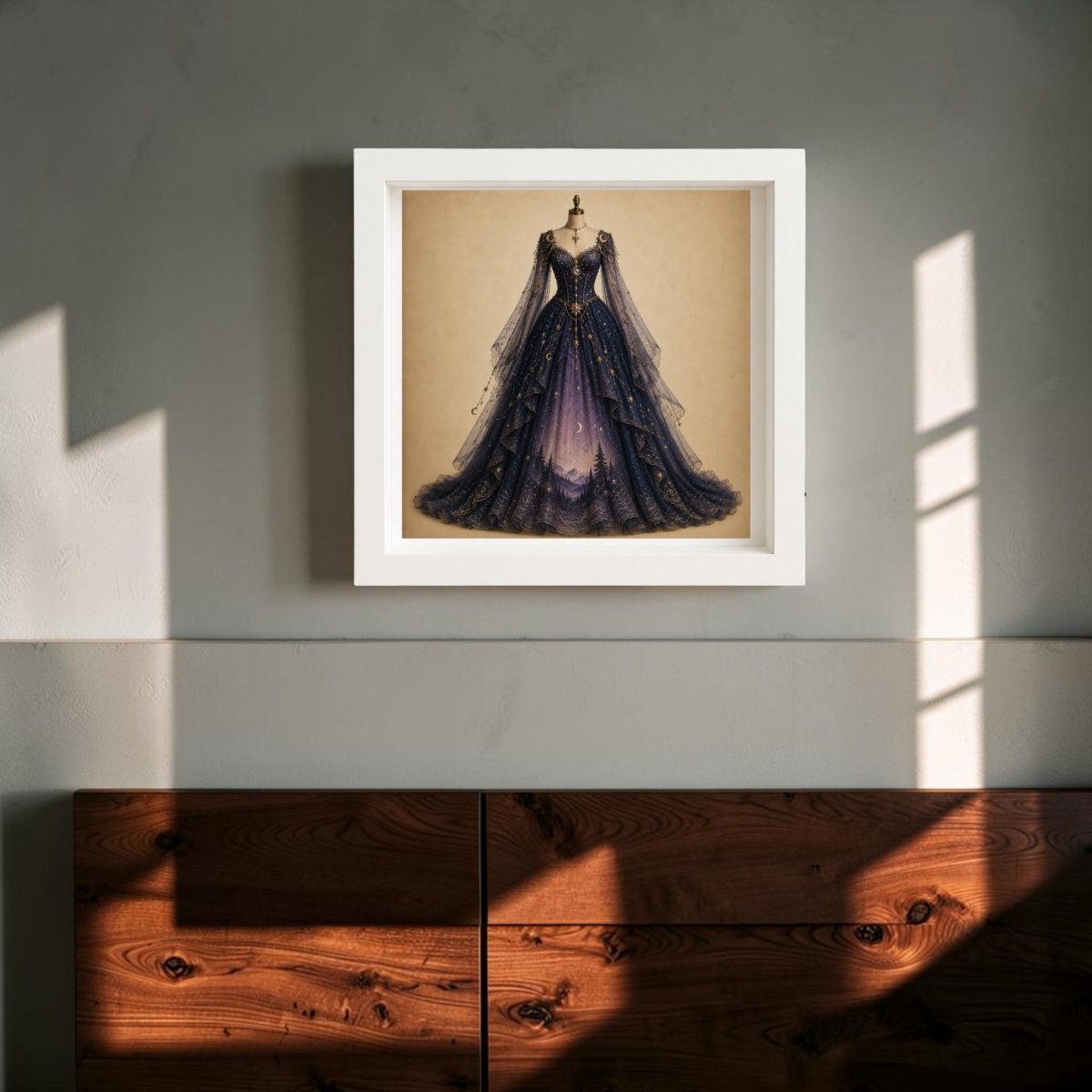 A framed print of “Moonrise Over Pines | Curated Couture Artwork” by Mirabilia Boutique, featuring an ornate celestial gown in deep, dark blue, hangs on a gray wall above a wooden cabinet. Sunlight streams in, casting shadows that accentuate the decorative artistry of this collectible framed canvas from Mirabilia Boutique.