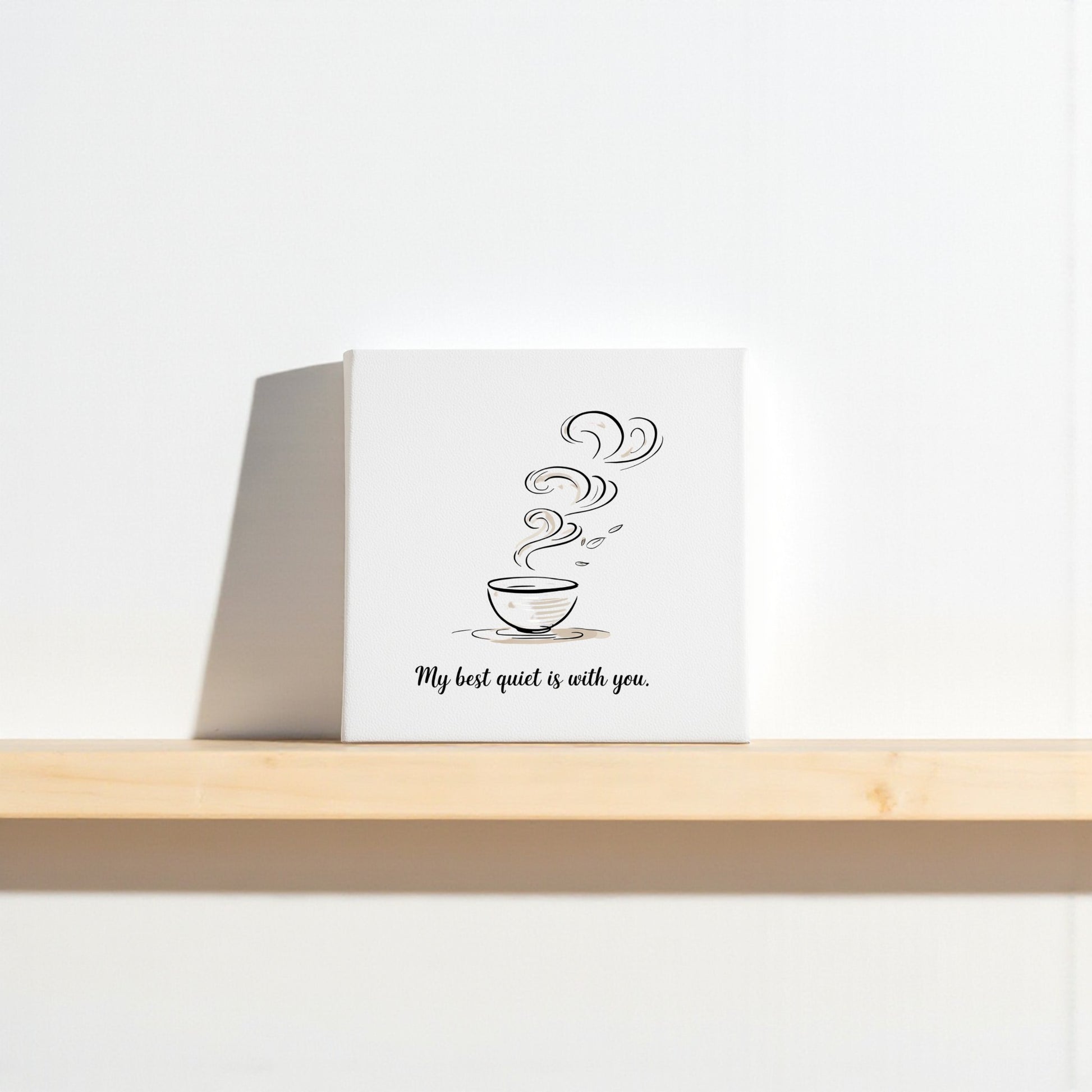 The "Best Quiet Canvas" by Mirabilia Boutique features a minimalist steaming cup and the quote "My best quiet is with you," making it an ideal sentimental gift or minimalist wall art for any space.