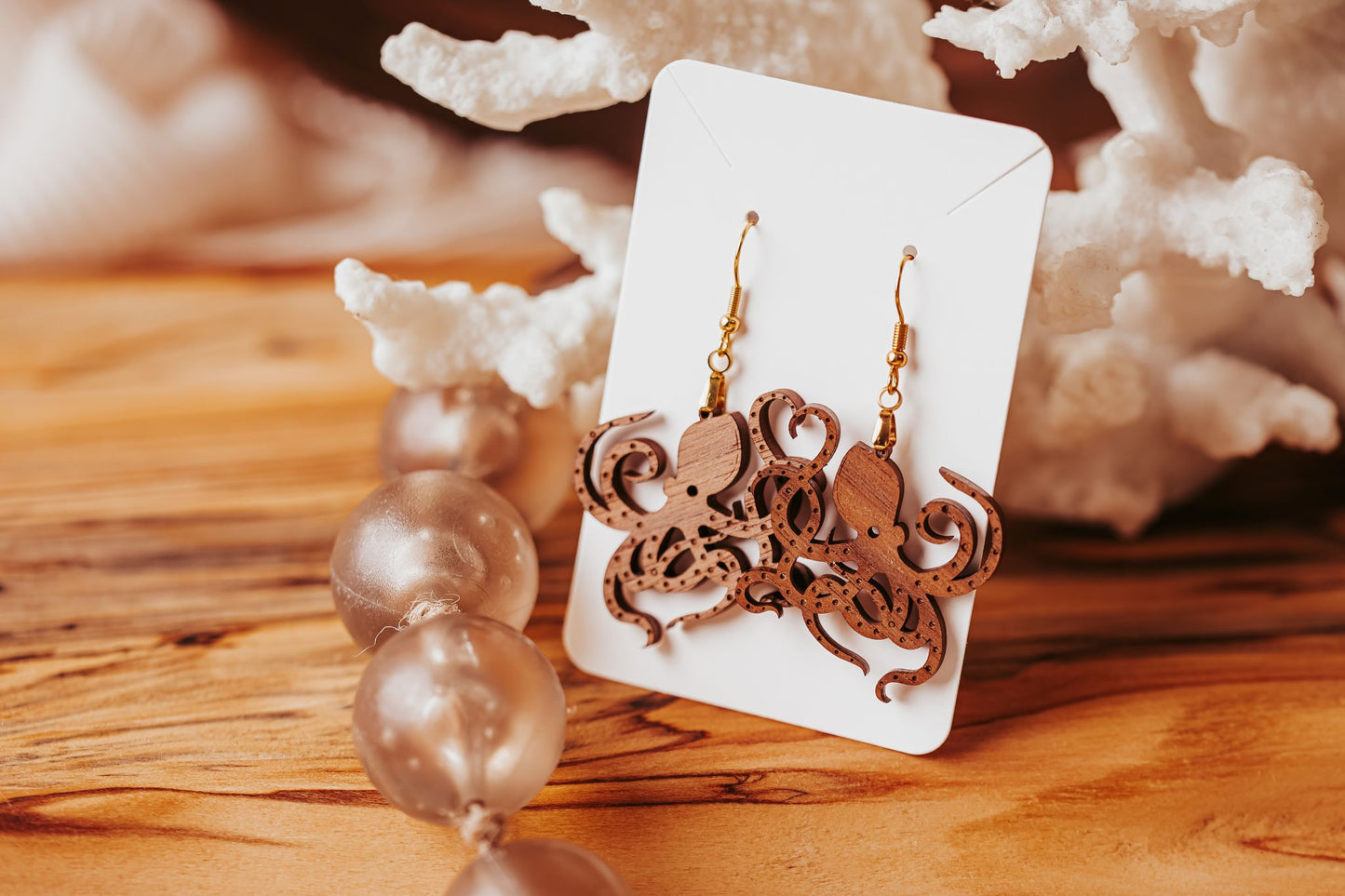 Octopus Earrings by Mirabilia Boutique—laser cut wood ocean jewelry—are displayed on a white card with beads and coral accents, making a perfect gift for nature or sea life lovers.