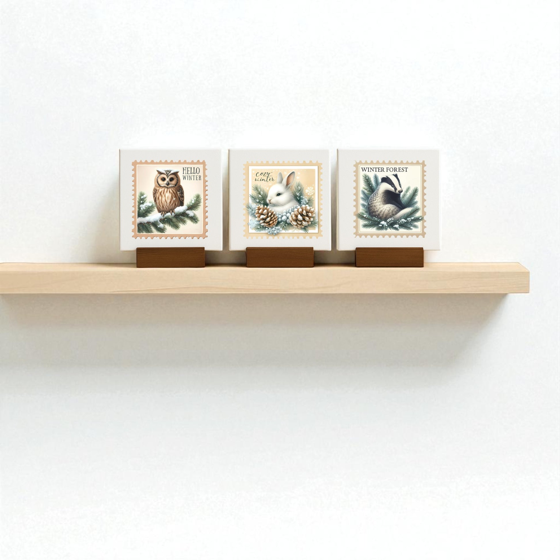 The Winter Forest Mini Sign Trio by Mirabilia Boutique features 4x4 canvas prints of an owl, rabbit, and black bird in soft pastels. These animal art pieces are perfect for adding cozy woodland charm to your winter decor or seasonal displays.