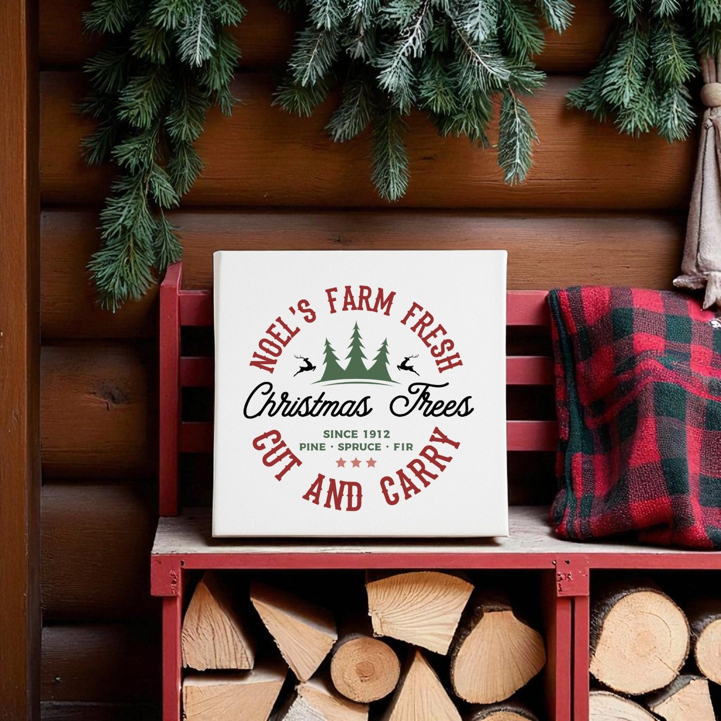 The Mirabilia Boutique Farm Fresh Christmas Tree Sign, a rustic holiday 8x8 canvas, sits on a red bench with firewood and plaid blanket by a log wall and evergreens, adding cozy farmhouse charm to your Christmas decor.