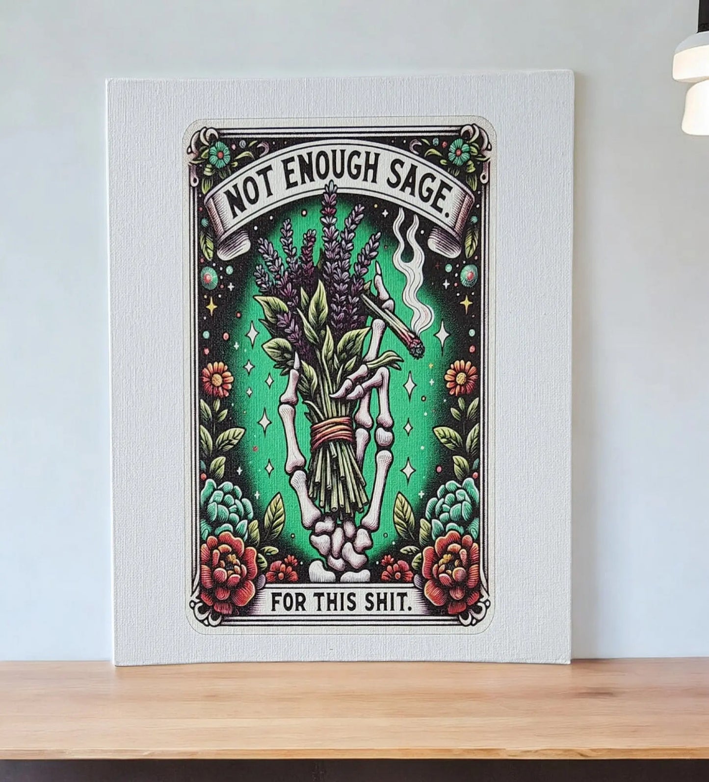 The Mirabilia Boutique's Humorous Sage Quote Wall Art Print for Home or Office Decor features a vibrant design of a hand holding sage, surrounded by flowers and stars. Set against a green background, it humorously displays the phrase "Not Enough Sage For This Shit." Perfectly placed on a wooden shelf, this witty artwork makes an ideal humorous gift.