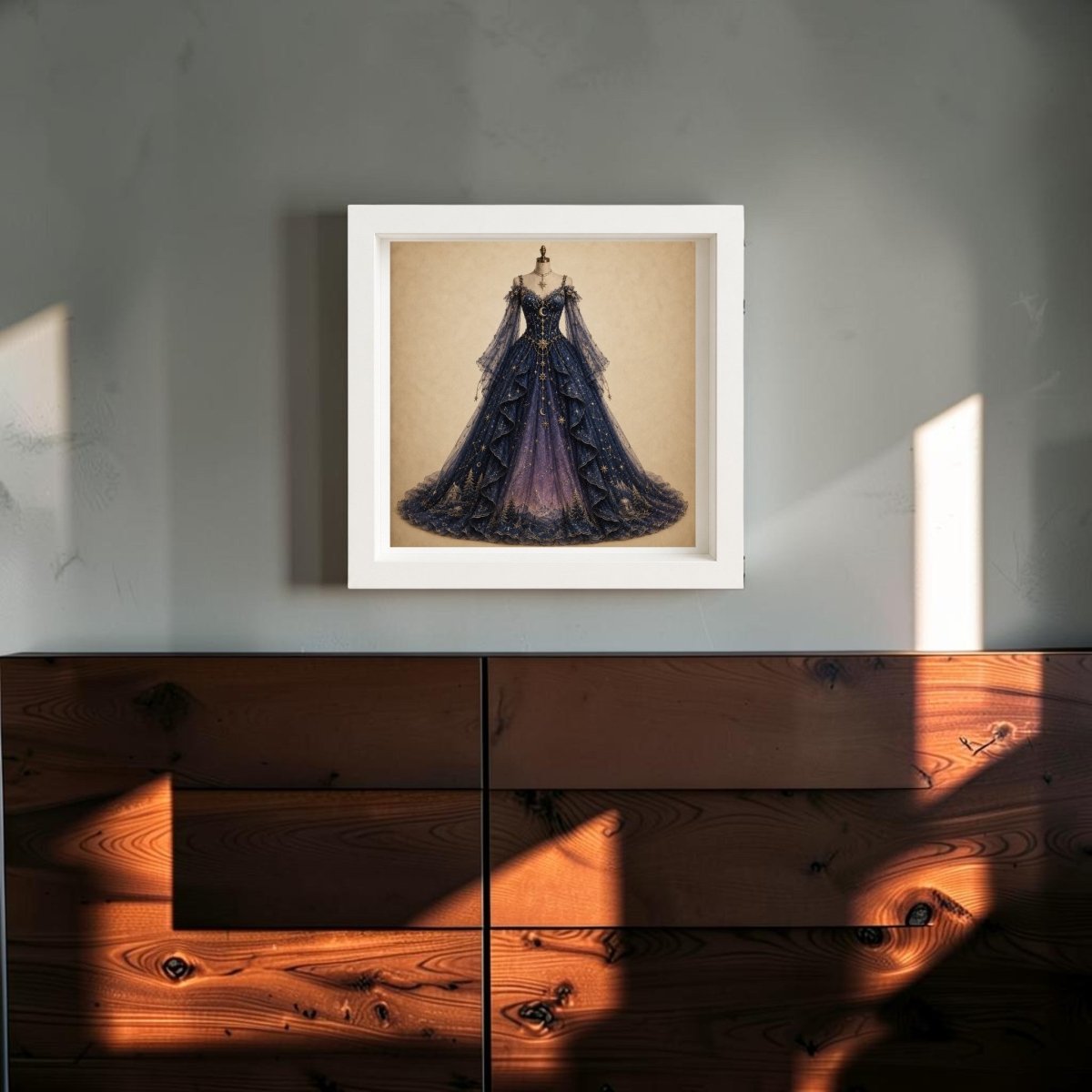 Under The Turning Stars | Curated Couture Artwork by Mirabilia Boutique features a framed depiction of an elegant, dark blue ball gown with intricate details, hanging on a gray wall above a wooden cabinet. Sunlight streams in, casting geometric shadows across the wall and wood surface. This collectible canvas art brings a sophisticated touch to any space.