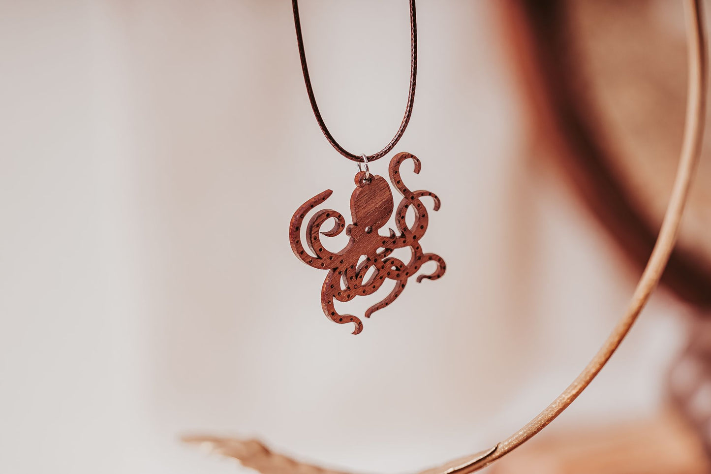 The Wooden Octopus Necklace by Mirabilia Boutique features a nautical pendant on a thin, dark cord—an elegant accessory for ocean lovers.